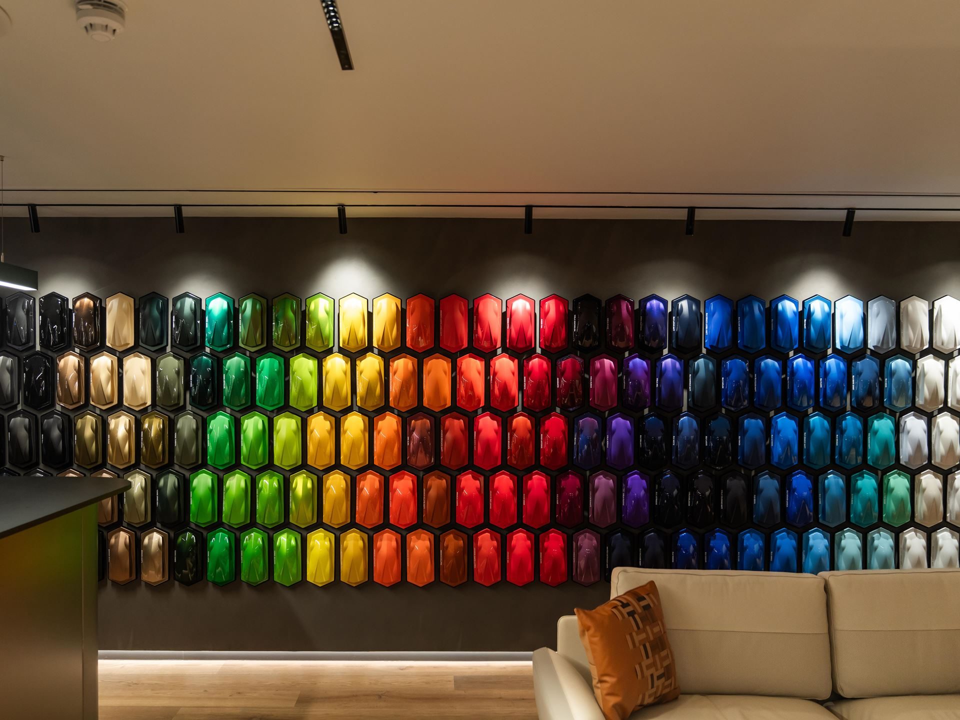 Lamborghini Plants Its Hybrid-Era Flag In Berkeley Square With Europe'S Most Extensive Ad Personam Display 3 Wide shot of the ad personam lounge showing a rainbow wall of hexagonal paint samples with a beige sofa in the foreground
