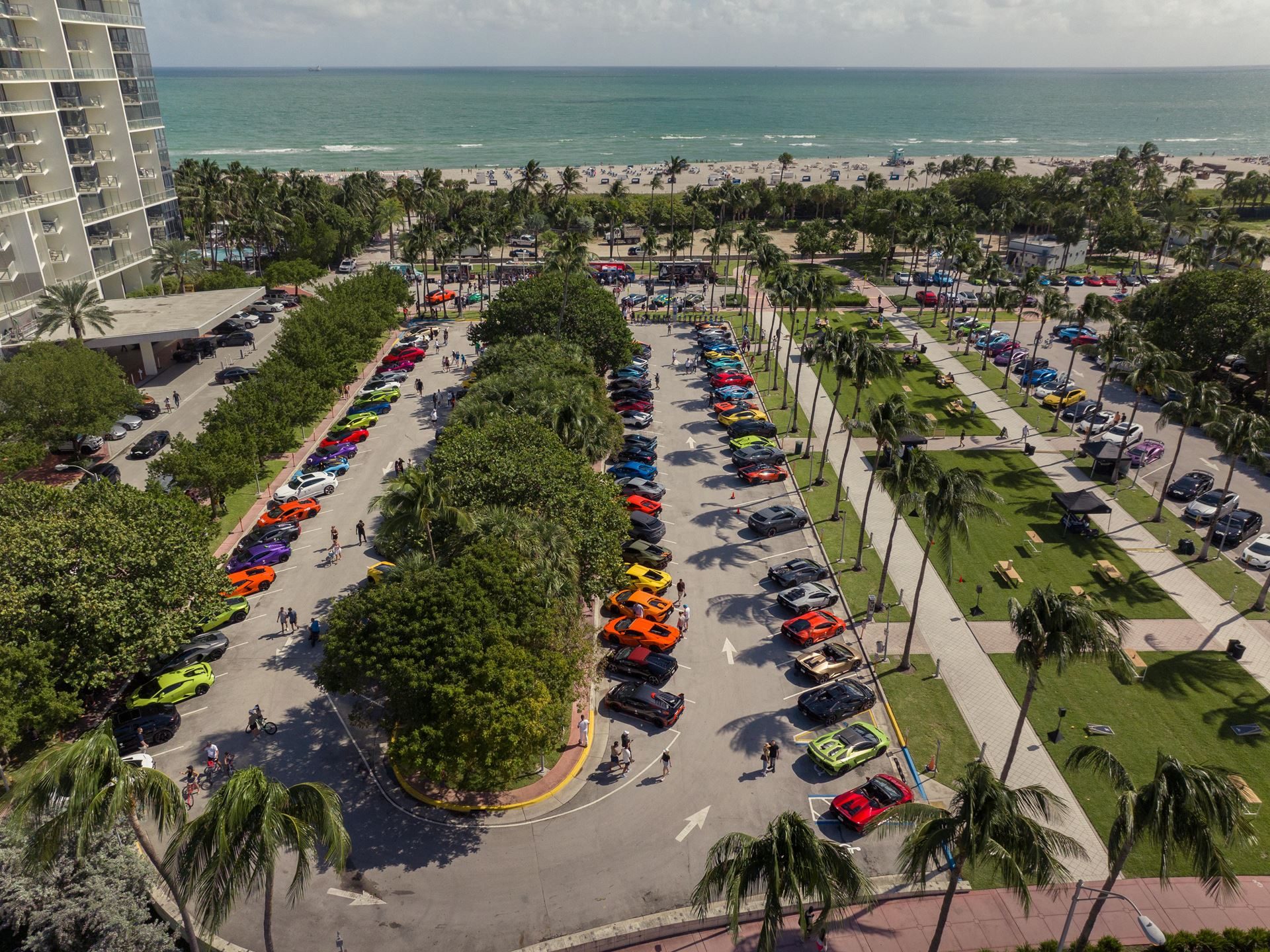 150 Mustache-Clad Lamborghinis Hit Miami As Movember Campaign Enters Year Four 9 Aerial view of a large gathering of colorful lamborghini vehicles parked in rows near a beach with people walking around