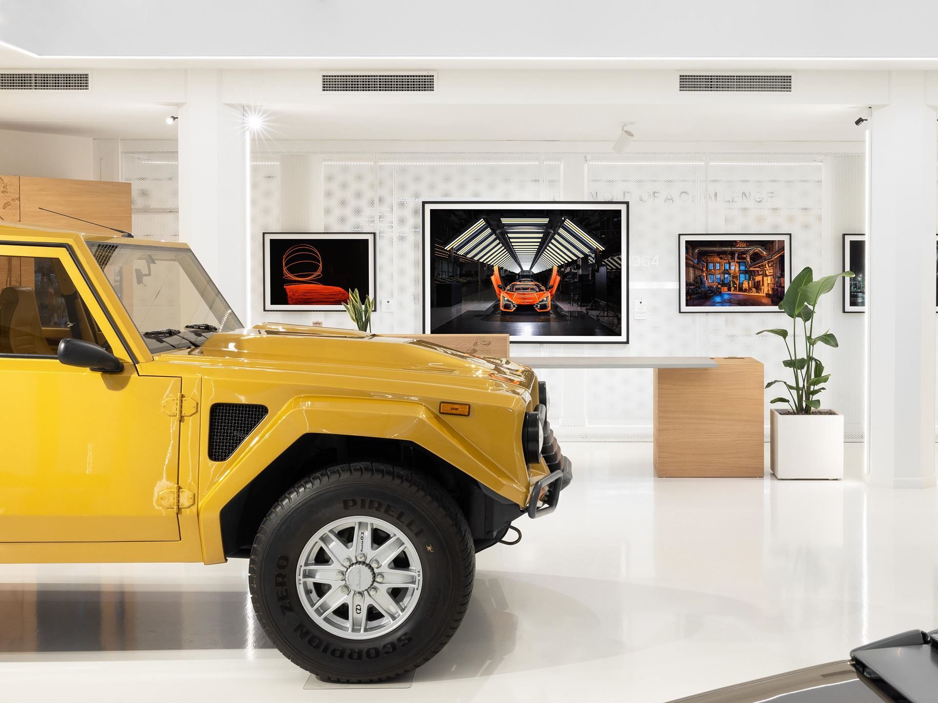 Lamborghini'S Museum Turns Its Own Factory Into Fine Art With Lucrezia Roda'S 'The Industrial Perspective' 7 A yellow lamborghini lm002 displayed in the museum with framed industrial art including a huracán factory photograph on the wall behind it
