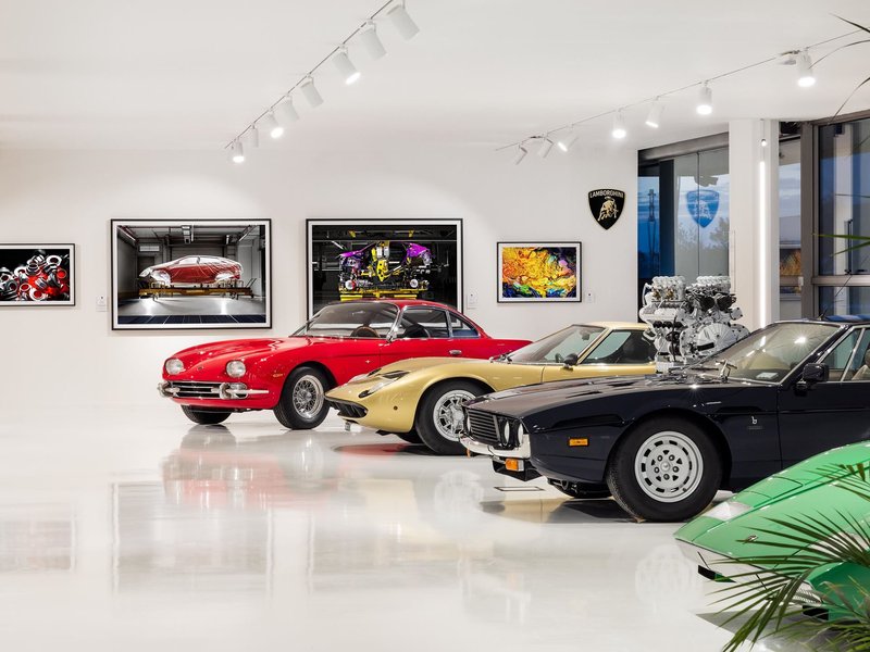 Classic Lamborghini models including a red 400 GT, gold Miura, blue Jarama, and green Urraco displayed alongside framed industrial photography at the Automobili Lamborghini Museum