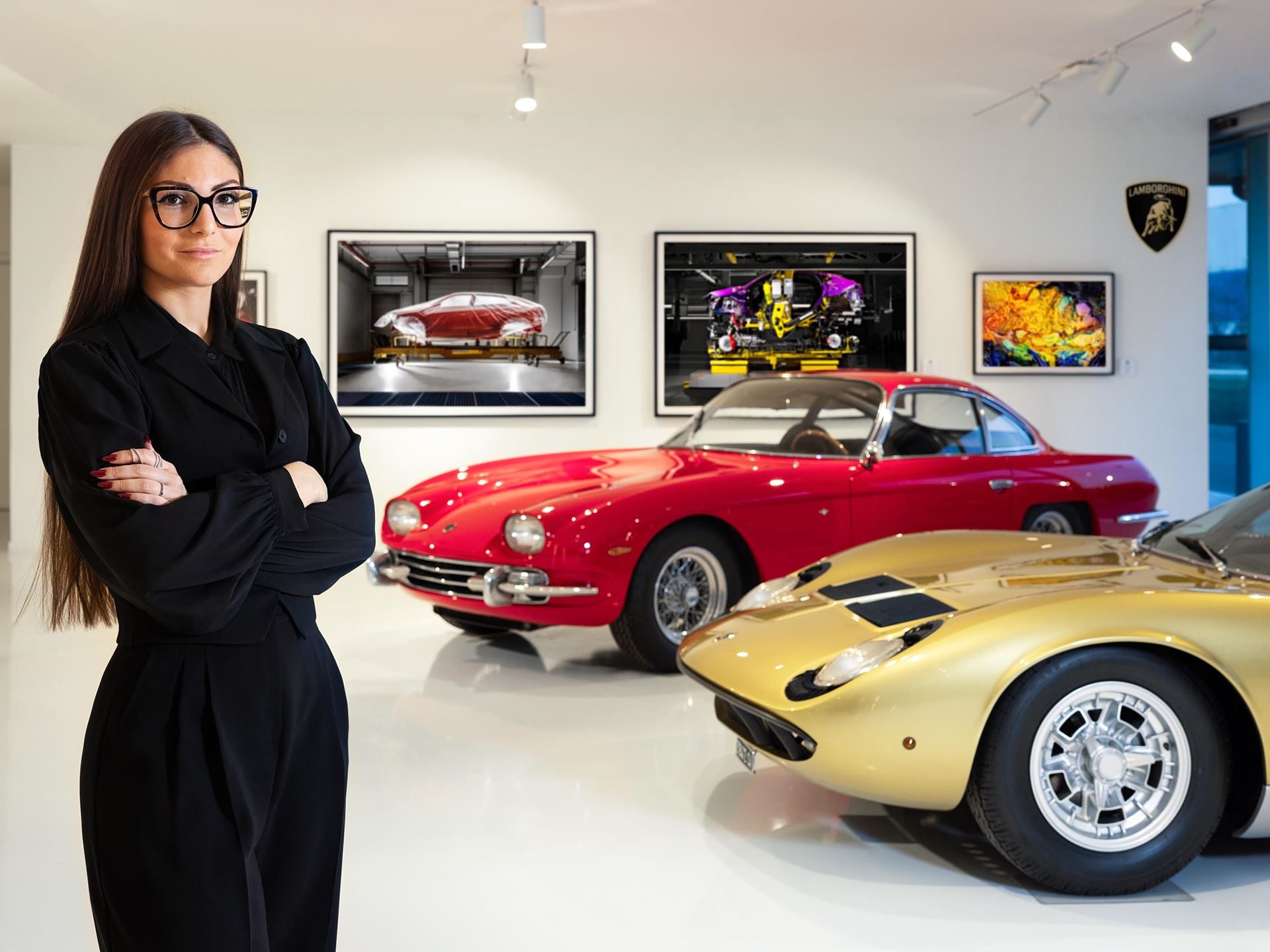 Lamborghini'S Museum Turns Its Own Factory Into Fine Art With Lucrezia Roda'S 'The Industrial Perspective' 9 Artist lucrezia roda standing in the automobili lamborghini museum with a red 350 gt and gold miura visible behind her alongside framed industrial photography