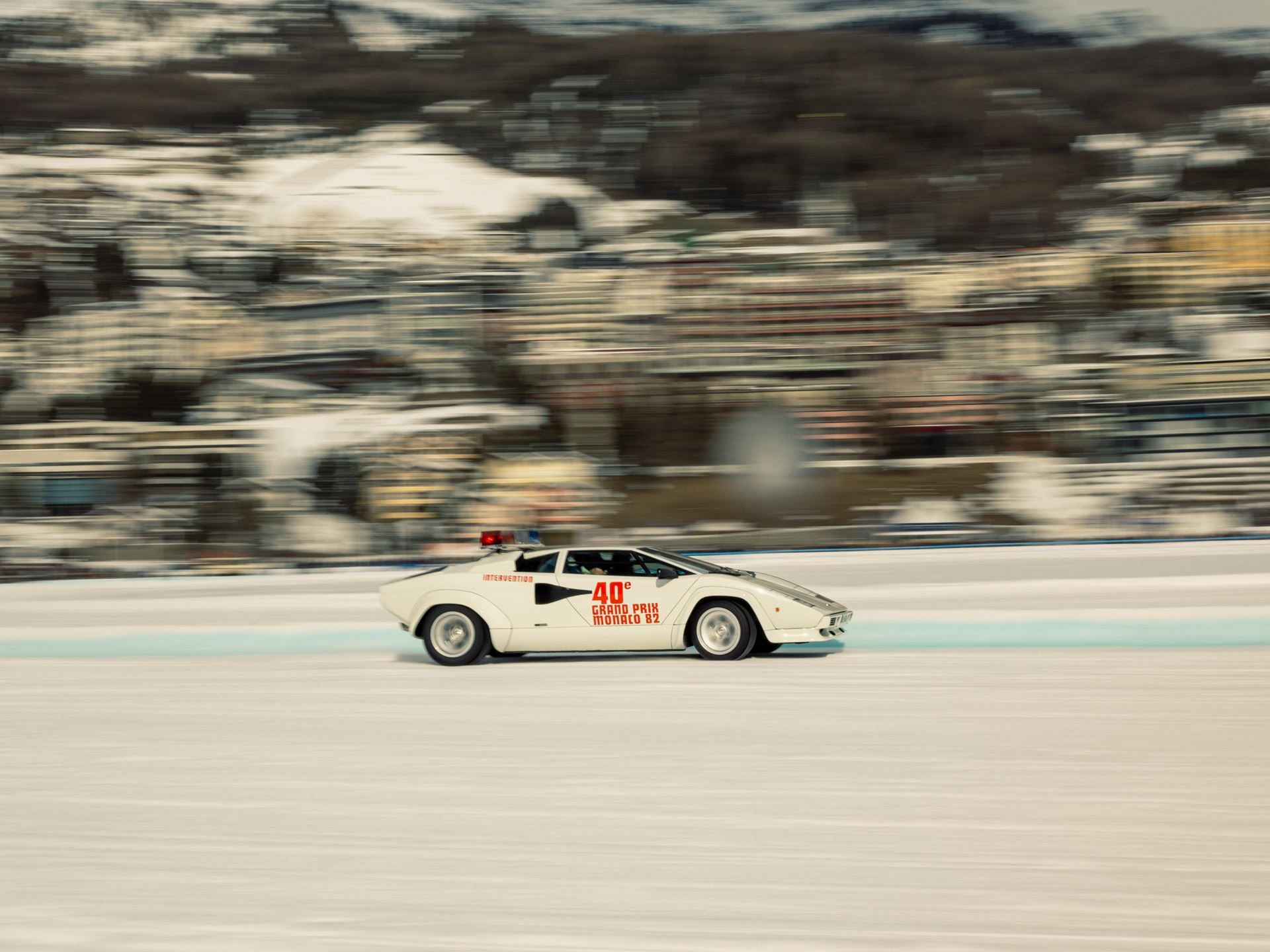 White lamborghini countach lp 400s pace car with monaco grand prix livery driving on a snowy track in st. Moritz