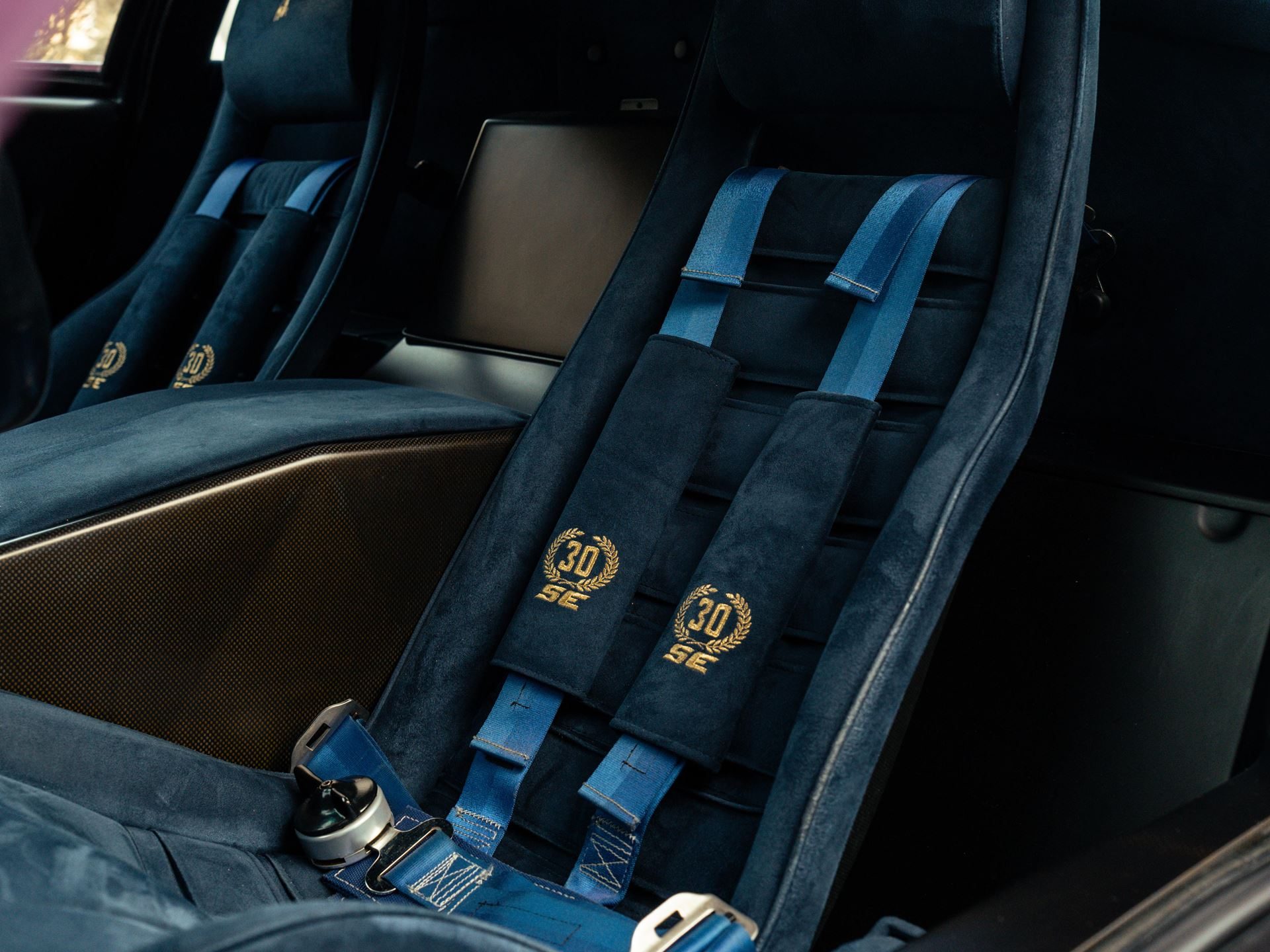 Close-up of blue alcantara racing seats with embroidered 30 se logos and blue racing harnesses inside the lamborghini diablo se30