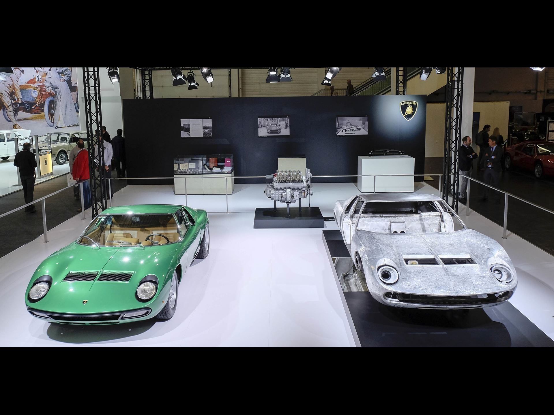 Ten Years Of Polo Storico: How Lamborghini Built The Only Heritage Program That Rebuilds Cars From The Dead 5 Two lamborghini miuras displayed side by side, one fully restored in green and one in bare metal, with a v12 engine on a pedestal between them