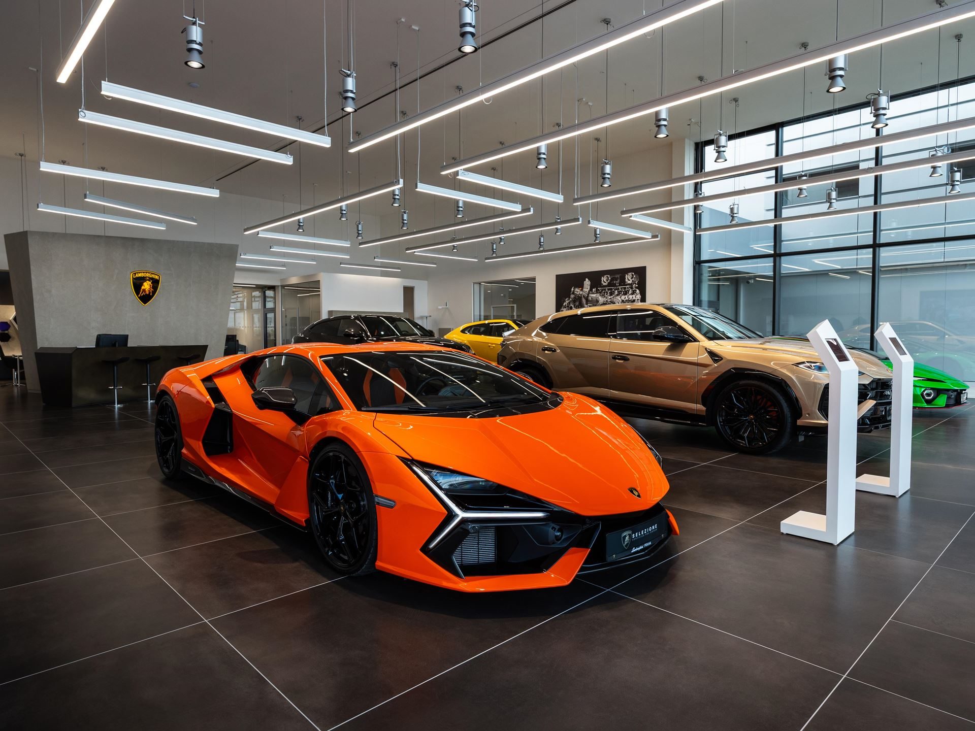 Lamborghini Prague Moves To Ořech With Fenomeno, Temerario, And A Full Hybrid Lineup On Display 3 Orange lamborghini revuelto displayed prominently in the new prague showroom alongside a gold urus and green huracán sto