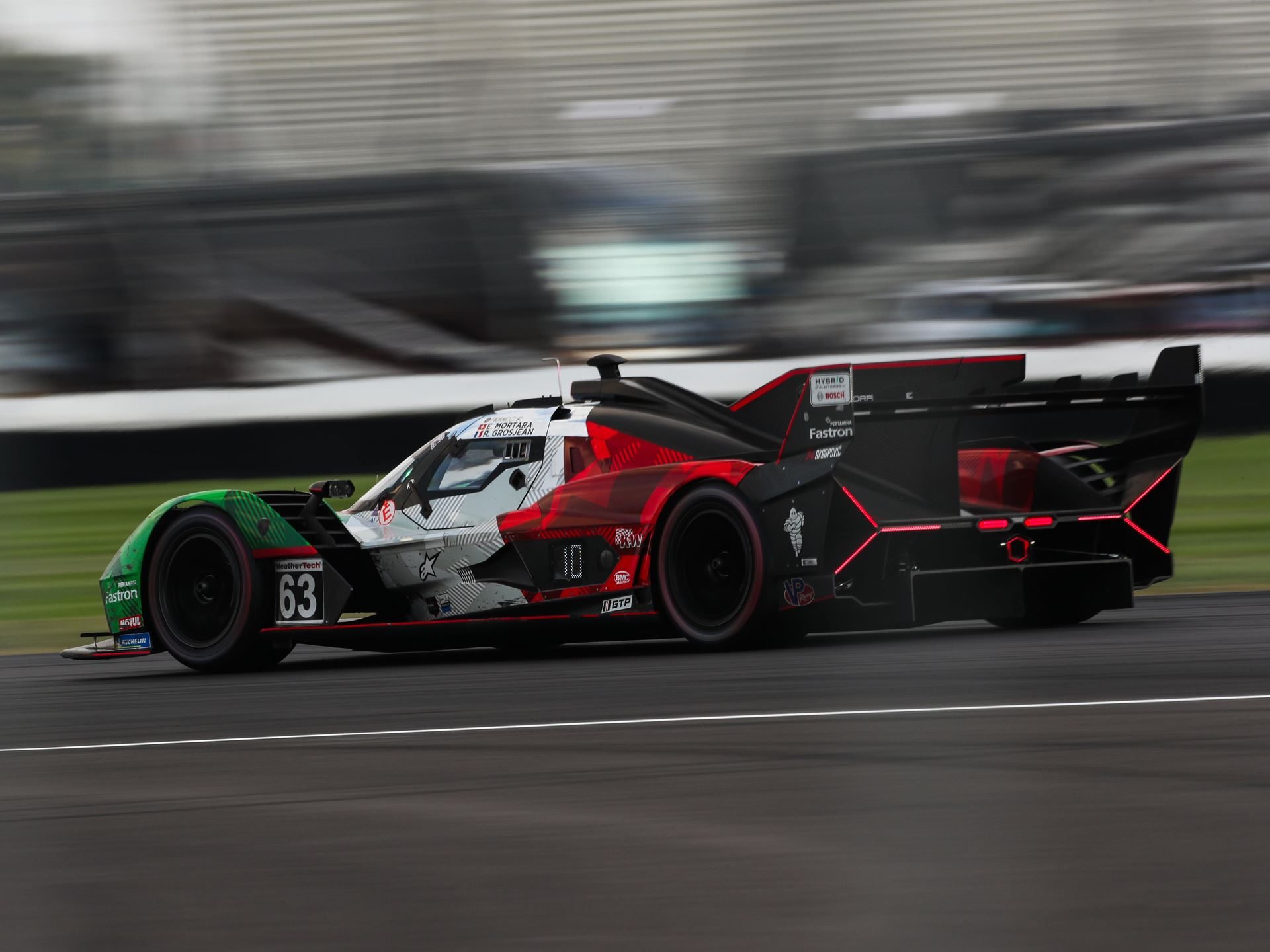 Kvyat Rejoins Grosjean And Mortara As The Lamborghini Sc63 Heads To Its Last Imsa Gtp Start 3 Lamborghini sc63 lmdh race car at speed on a racetrack with motion blur highlighting its sleek profile and prominent rear wing