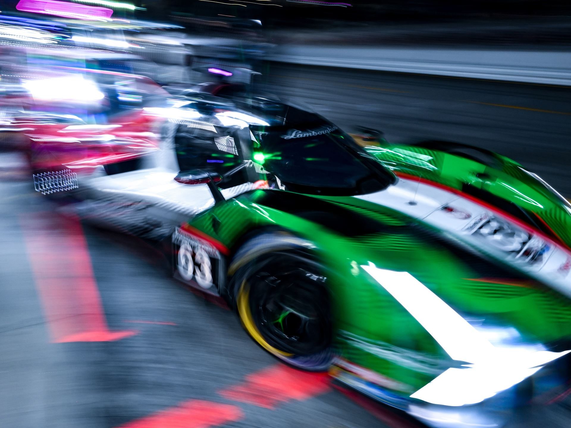 High-angle motion-blurred shot of the lamborghini sc63 racing at night with bright headlights cutting through the darkness