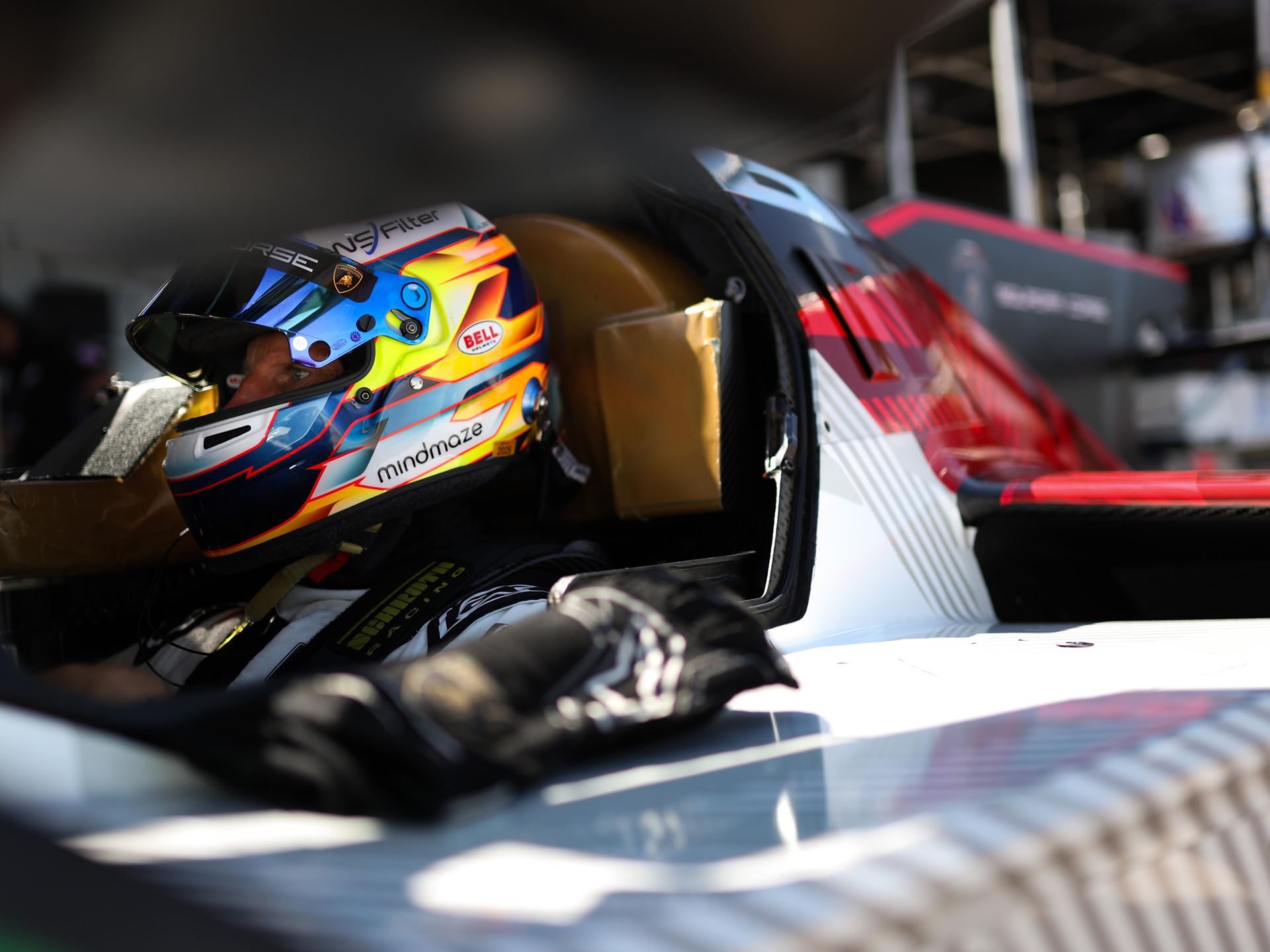 Lamborghini Sc63 Returns To Its Breakthrough Circuit At Indianapolis, Carrying Watkins Glen Momentum 5 Race car driver seated in the cockpit of the lamborghini sc63 wearing a multi-colored helmet