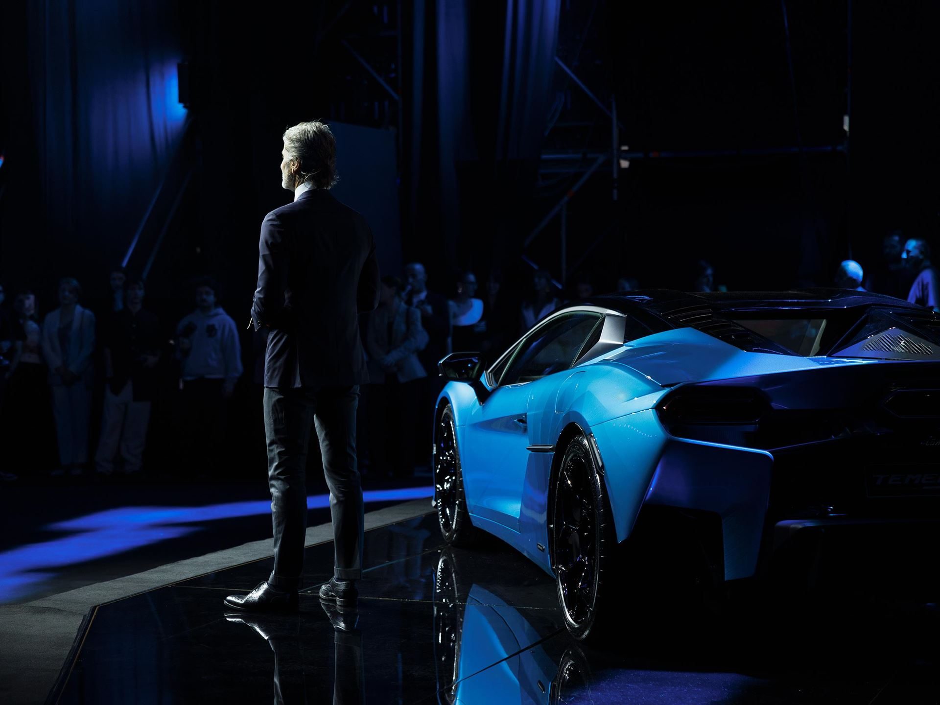 Lamborghini Opens Its First Official Showroom In Georgia, Premiering The Temerario In Tbilisi 7 Presenter on stage with the blue lamborghini temerario partially visible under dramatic lighting at the tbilisi event