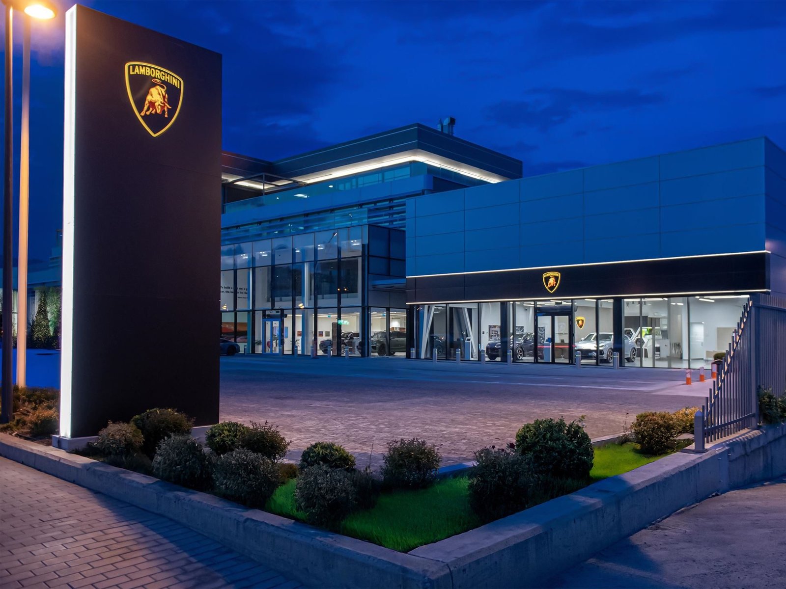 Exterior of the new Lamborghini showroom in Tbilisi, Georgia at dusk with illuminated branding and cars visible through glass windows