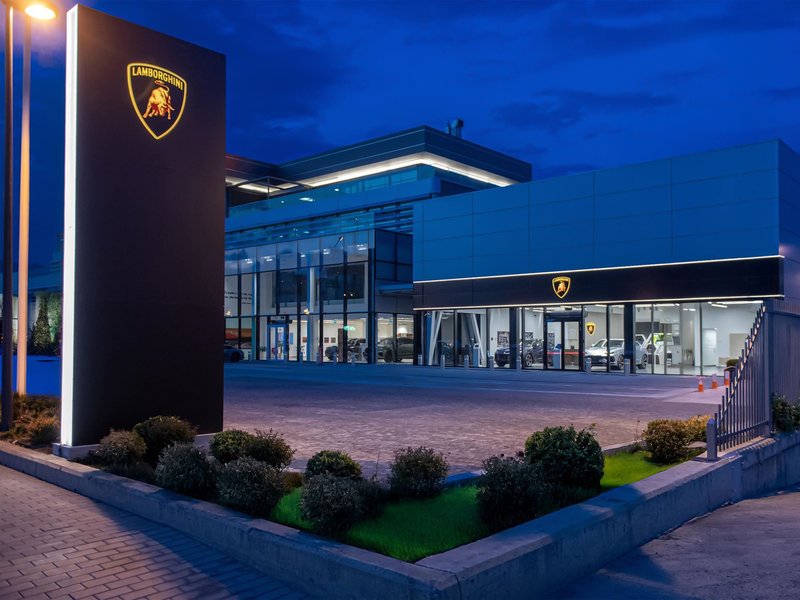 Exterior of the new Lamborghini showroom in Tbilisi, Georgia at dusk with illuminated branding and cars visible through glass windows