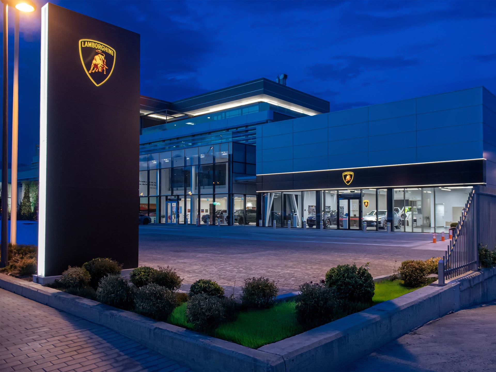 Exterior of the new lamborghini showroom in tbilisi, georgia at dusk with illuminated branding and cars visible through glass windows