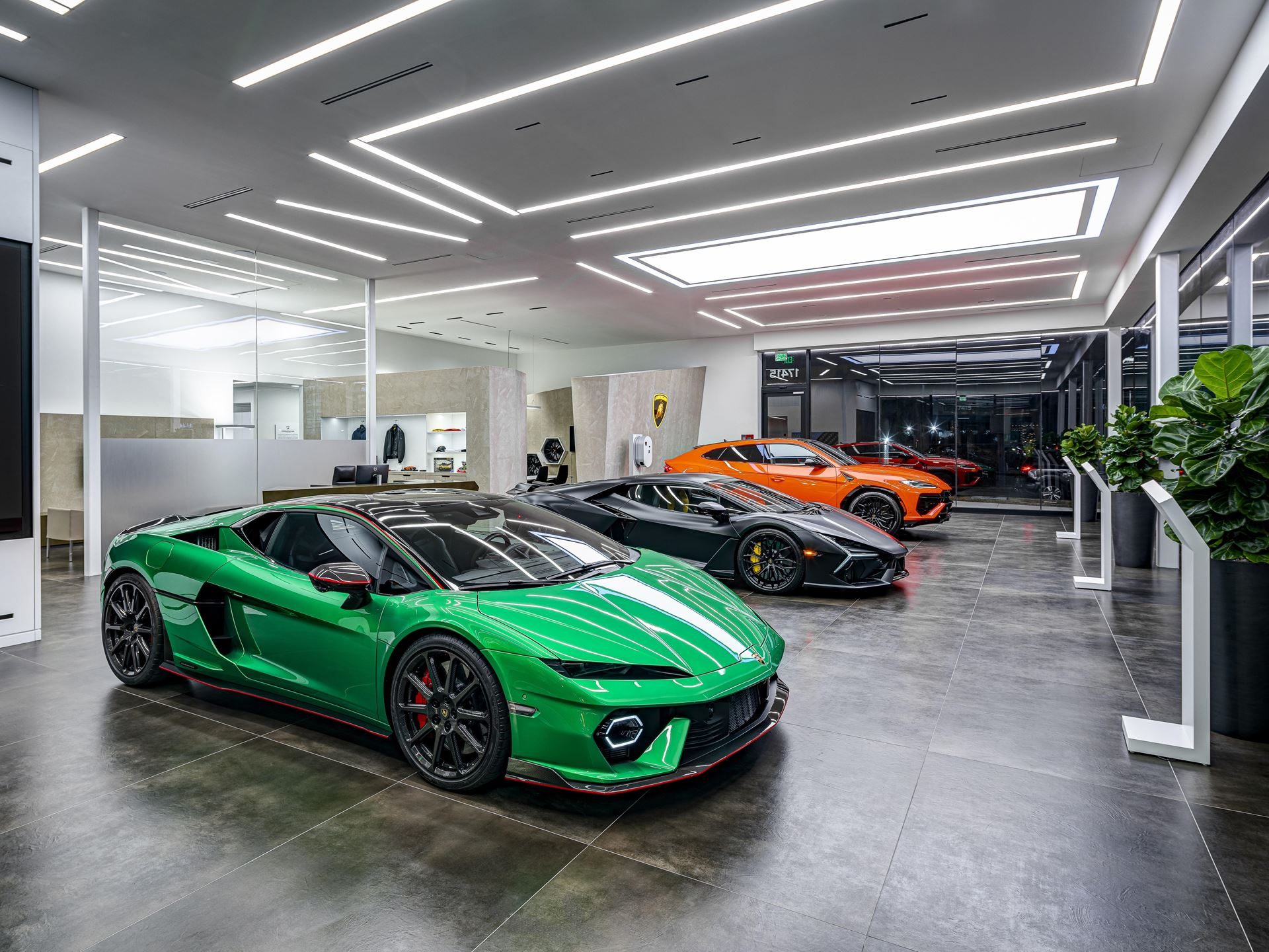 Lamborghini'S Temerario Brings A 10,000 Rpm V8 To Florida'S Seventh Showroom 5 Interior of lamborghini south dade showroom displaying a green huracán sto, dark grey revuelto, and orange urus under sleek modern lighting