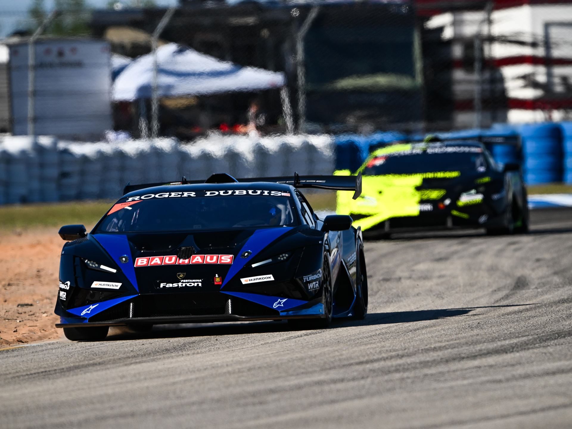 41 Huracáns Head To Laguna Seca As Wayne Taylor Racing Carries Five-Win Sebring Momentum 5 A black and blue lamborghini huracán super trofeo evo2 race car leading another car through a corner on a race track