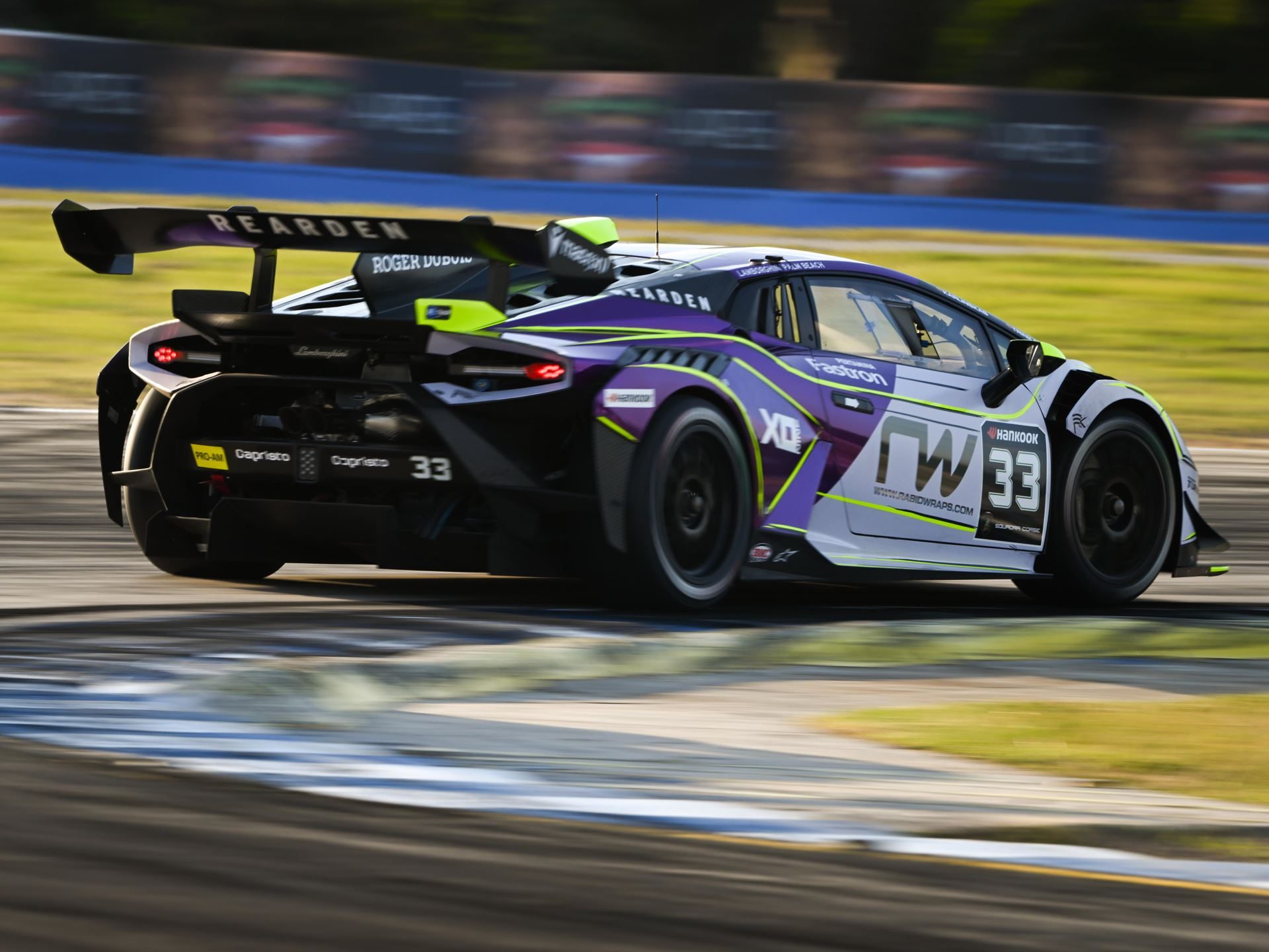 41 Huracáns Head To Laguna Seca As Wayne Taylor Racing Carries Five-Win Sebring Momentum 11 A purple, white, and black lamborghini huracán super trofeo evo2 race car with neon green accents speeding on track, showing its massive rear wing and diffuser