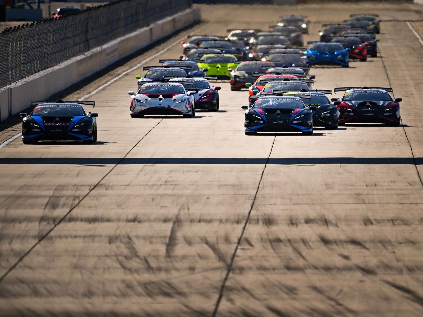 A packed grid of Lamborghini Huracán Super Trofeo EVO2 race cars lined up on track under bright sunlight before a race start