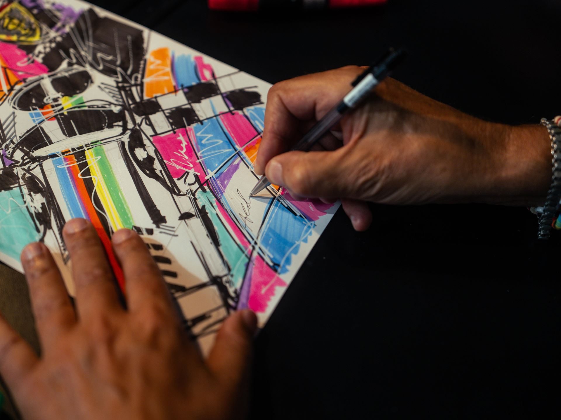 Why Lamborghini Puts The Revuelto Front And Center At Its Biggest Racing Weekend 5 Close-up of hands sketching and coloring a vibrant abstract design with pen and markers