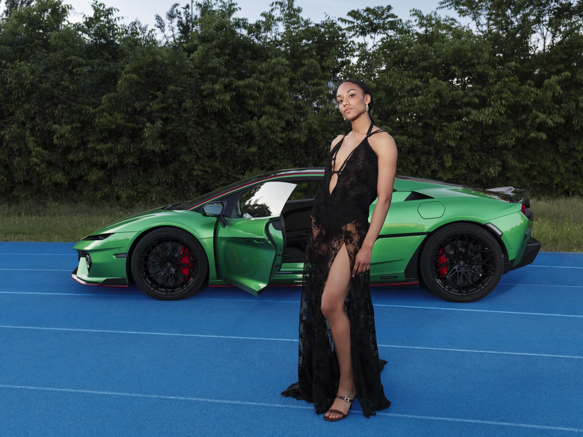 Lamborghini'S Temerario Campaign With Larissa Iapichino Sells The Physics Of The Split Second 9 A green lamborghini temerario with door open on a blue track surrounded by trees