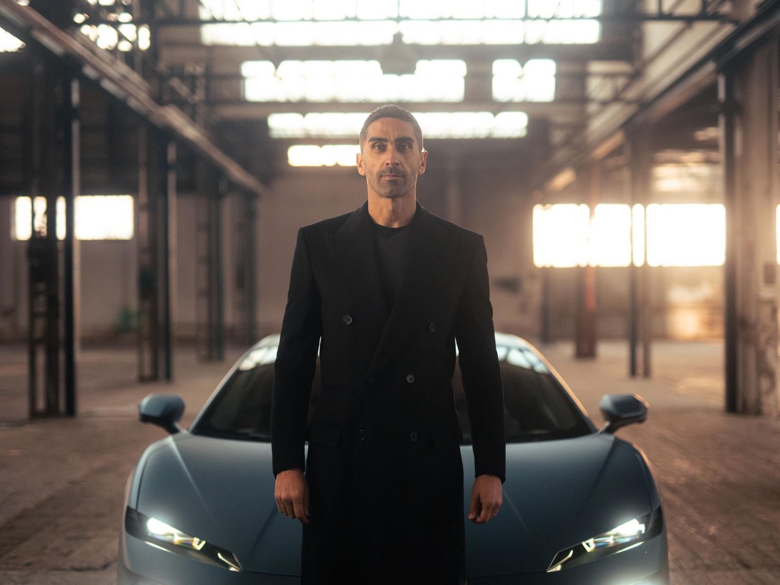 Matte blue Lamborghini Temerario in an industrial warehouse with Filippo Magnini standing nearby