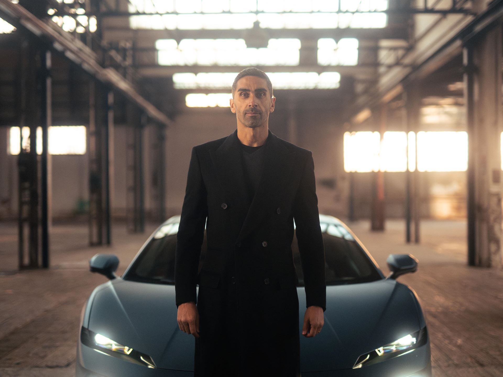 Matte blue lamborghini temerario in an industrial warehouse with filippo magnini standing nearby