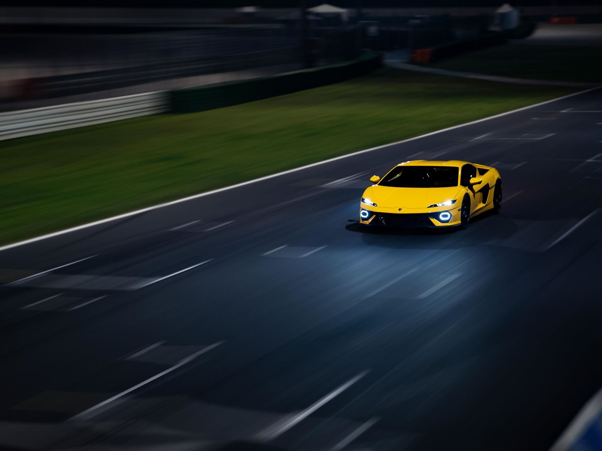 Yellow lamborghini temerario speeding on a dark racetrack at night with motion blur