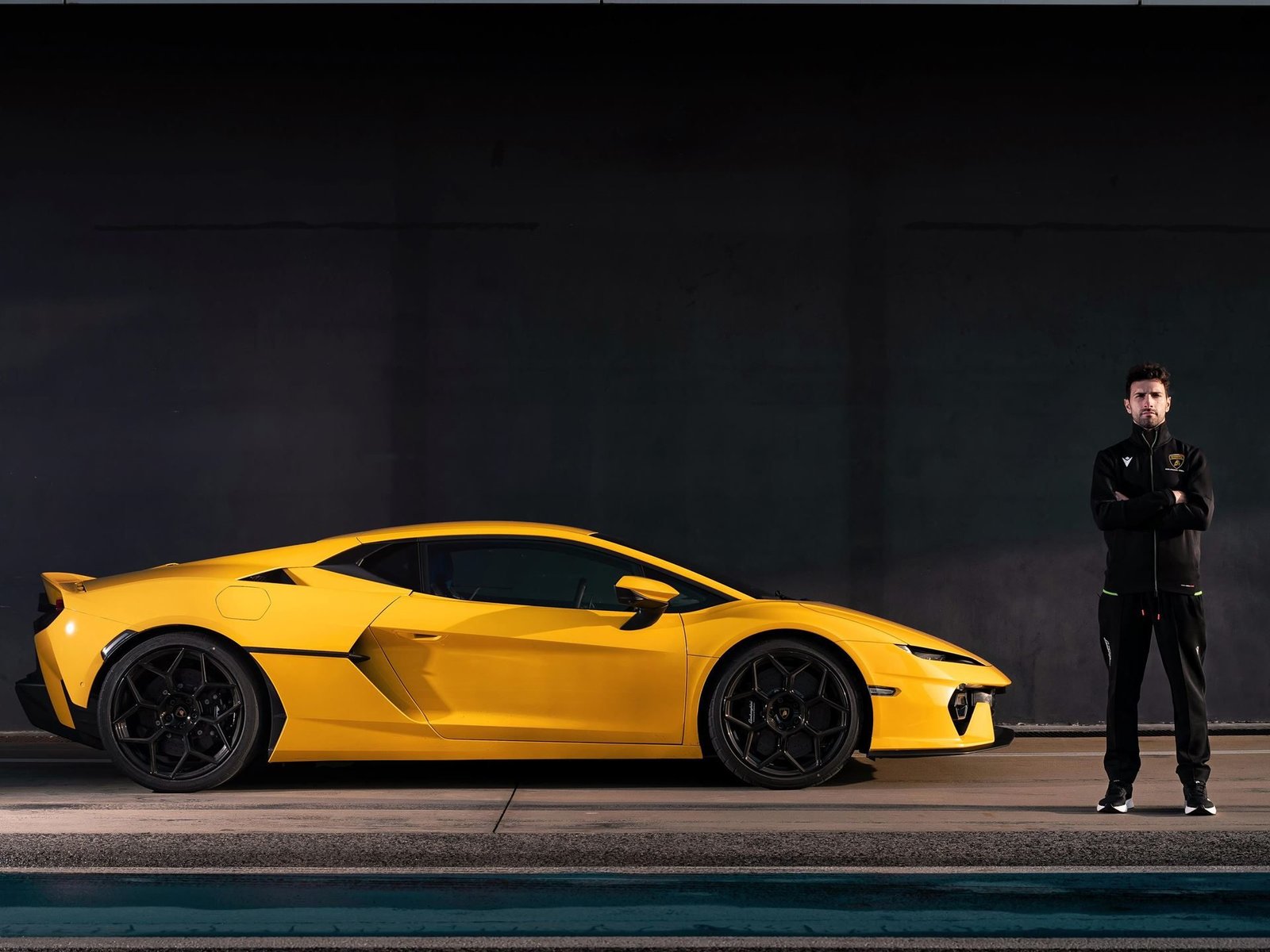 Squadra Corse factory driver Andrea Caldarelli standing beside a yellow Lamborghini Temerario on a racetrack