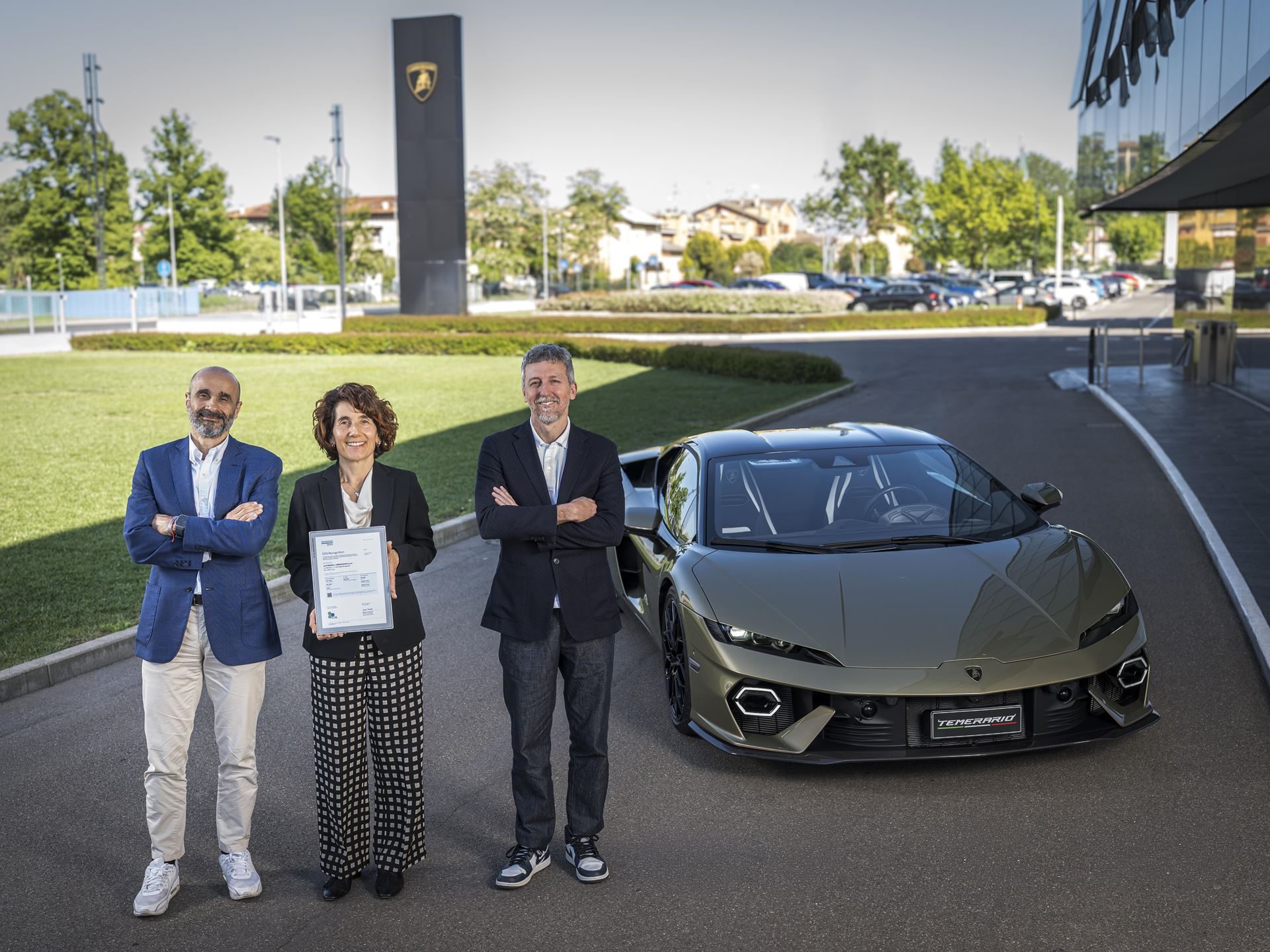 Three individuals holding a certificate at lamborghini headquarters during the dnv esg recognition presentation