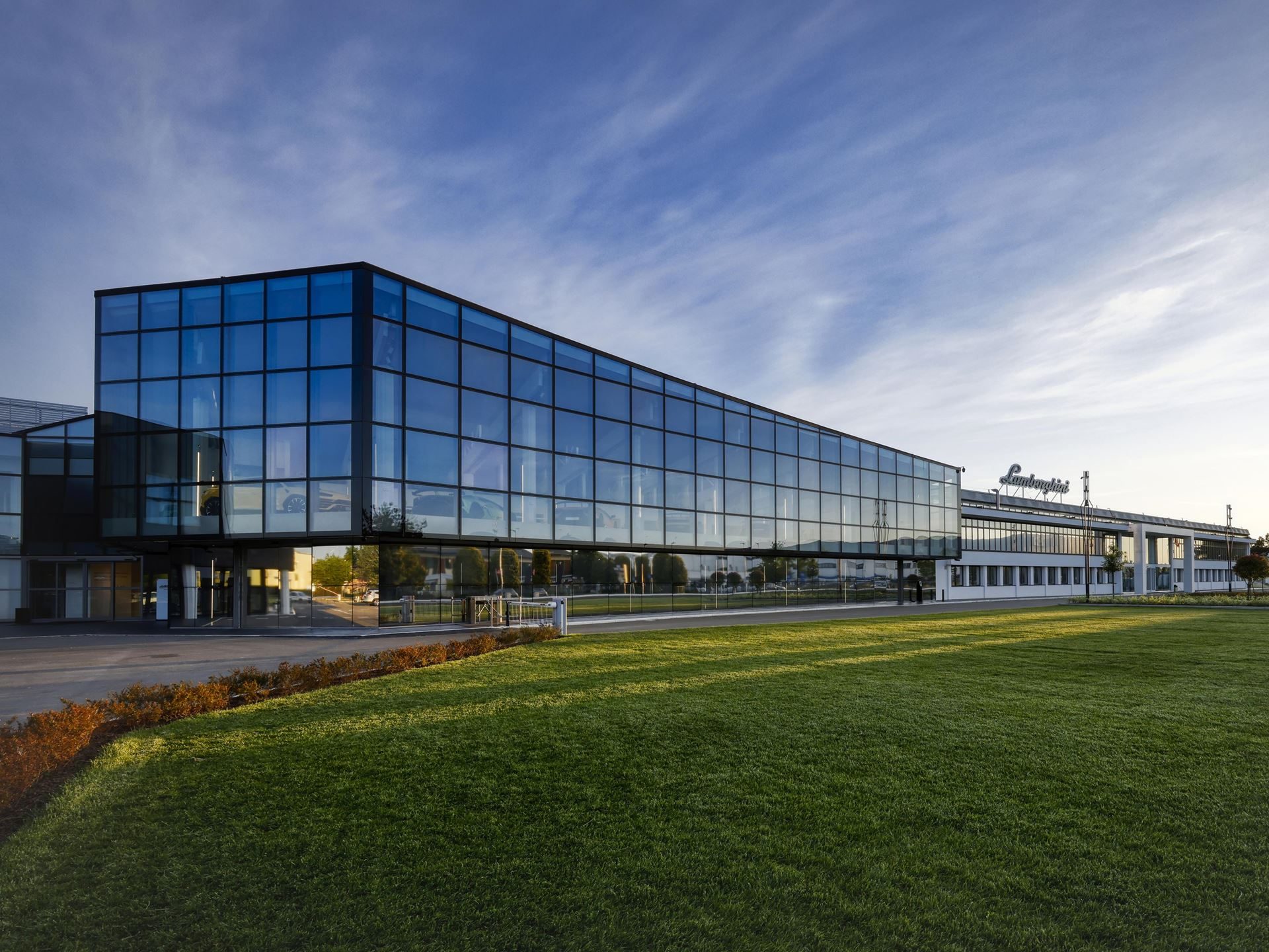 Exterior view of lamborghini's modern glass-fronted headquarters building in sant'agata bolognese