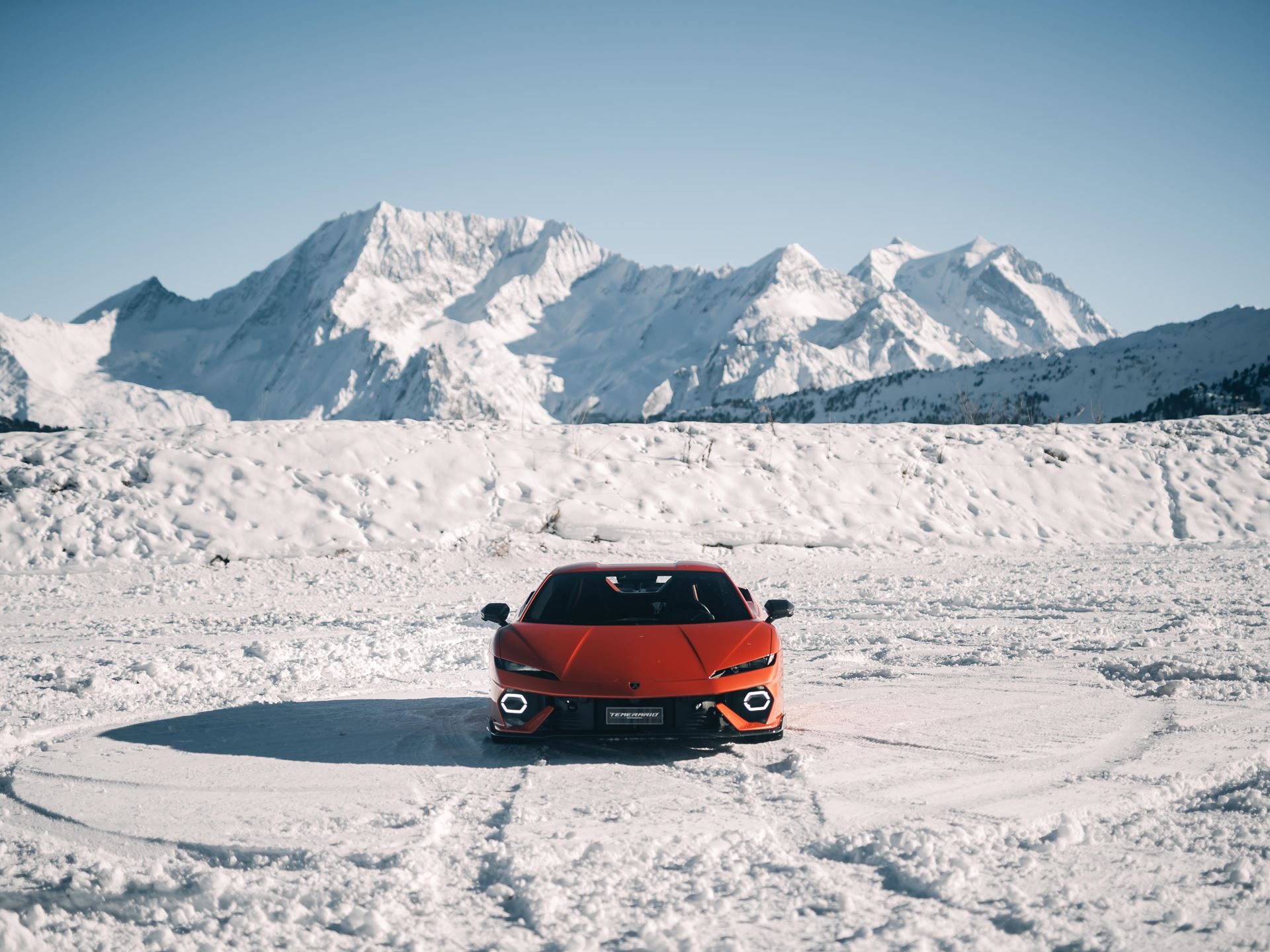 Lamborghini'S Temerario Drifts On Alpine Ice, Proving Its Hybrid System Works Where Grip Doesn'T 5 Orange lamborghini temerario parked on snow-covered expanse with snow-capped mountains