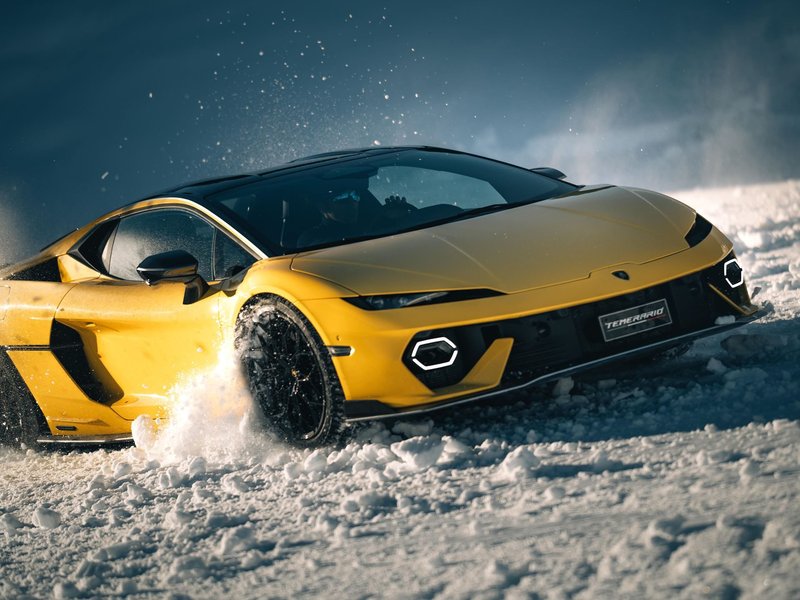 Yellow Lamborghini Temerario drifting on snow with spray from front wheels in the French Alps