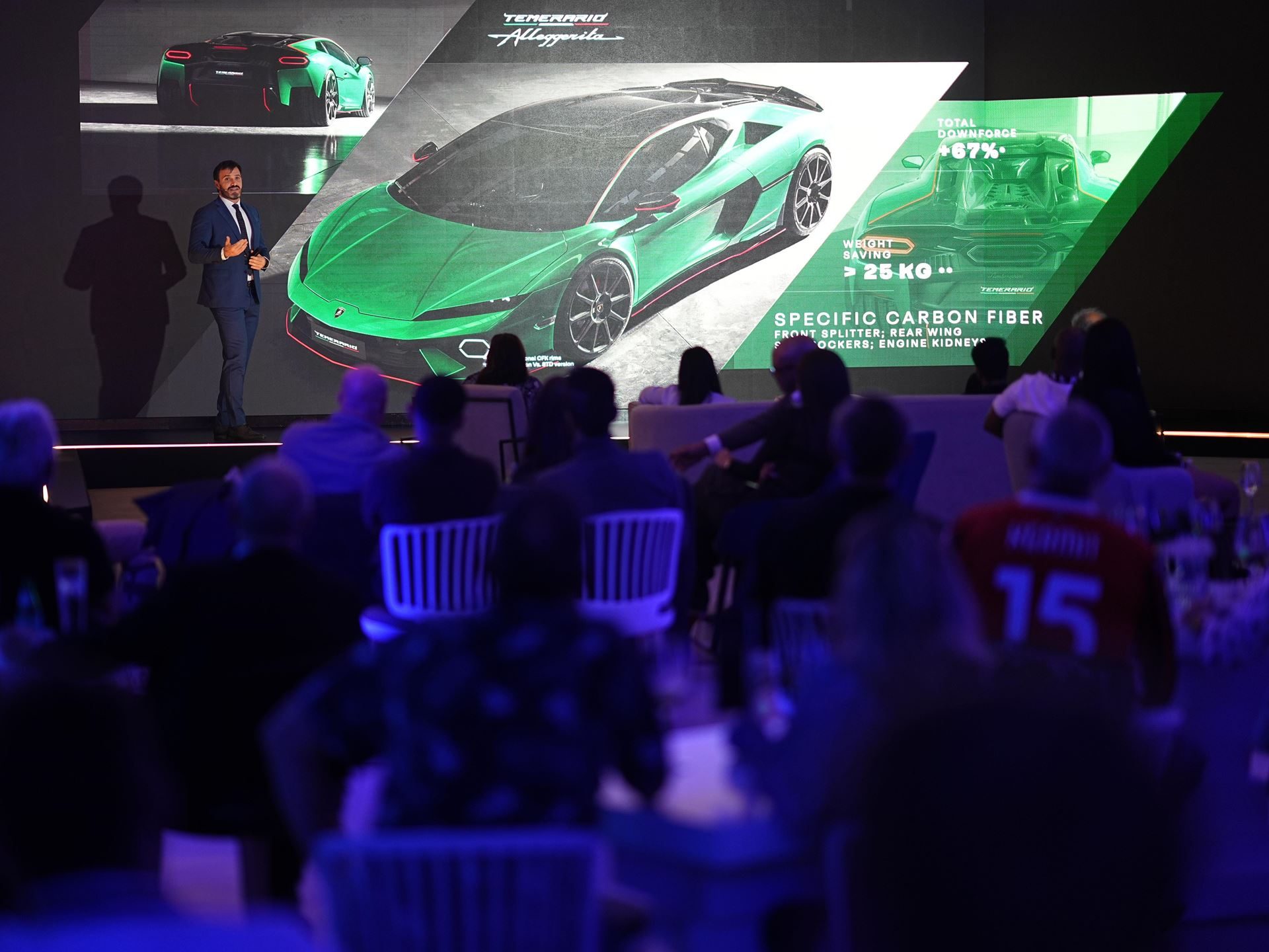 Lamborghini Temerario Arrives In Johannesburg With 920 Cv And A 10,000 Rpm V8 Hybrid 7 Presenter on stage at the temerario launch with technical diagrams showing 67 percent downforce increase and carbon fiber component details