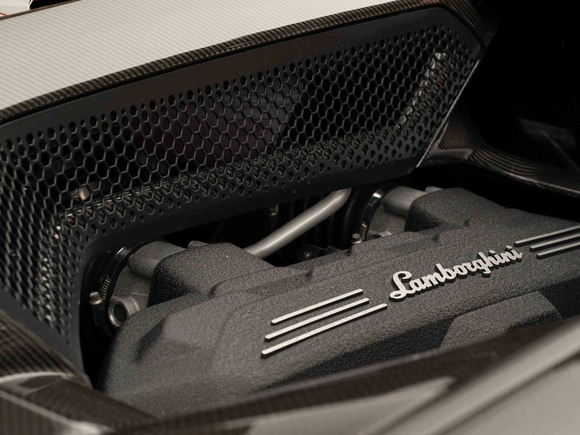 Close-up of the lamborghini temerario engine showing lamborghini script, honeycomb grille, and carbon fiber elements