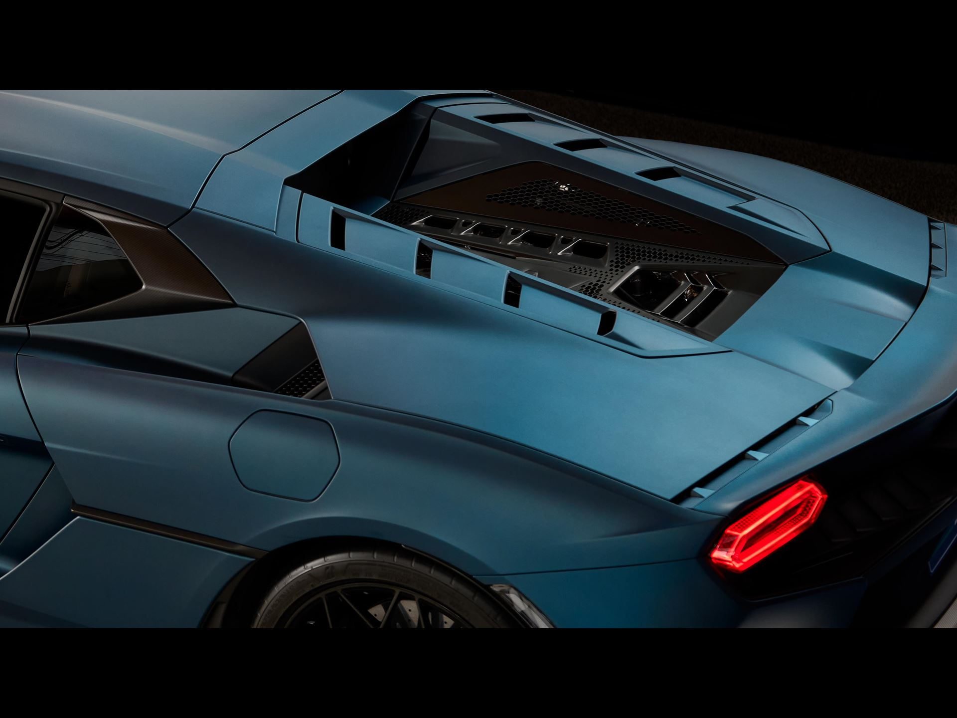 Overhead rear three-quarter view of the Lamborghini Temerario showing the engine cover grille and illuminated taillight in matte blue