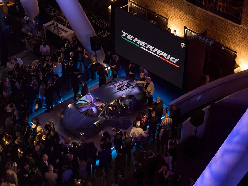 Overhead view of the Lamborghini Temerario debut event in Toronto with the car on an illuminated platform surrounded by attendees