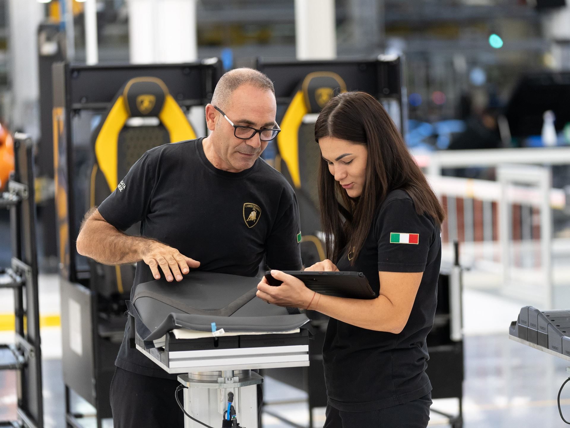 Lamborghini'S 12Th Consecutive Top Employer Award Reveals The Factory Floor Culture Behind Its Supercars 5 Two lamborghini employees inspecting a car seat component on the assembly line, with one holding a tablet and the other pointing at the seat