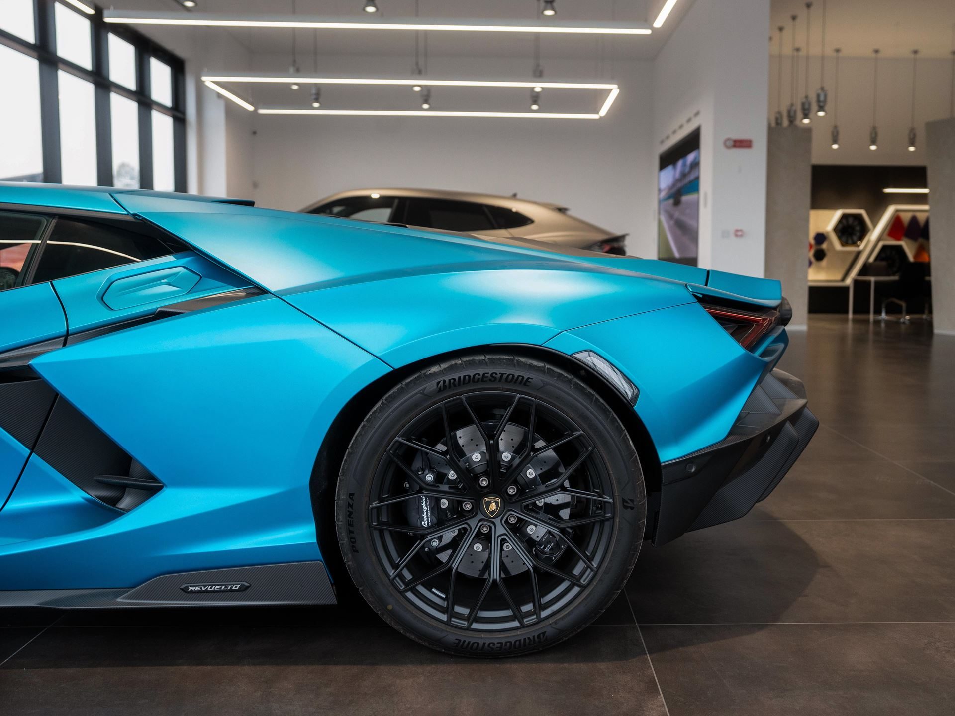 Lamborghini'S Seventh Italian Showroom Opens In Turin With 1,400 Square Meters And A 10,000-Rpm Centerpiece 7 Rear quarter view of a blue lamborghini revuelto showing wheel, brake caliper, and rear fender in the turin showroom
