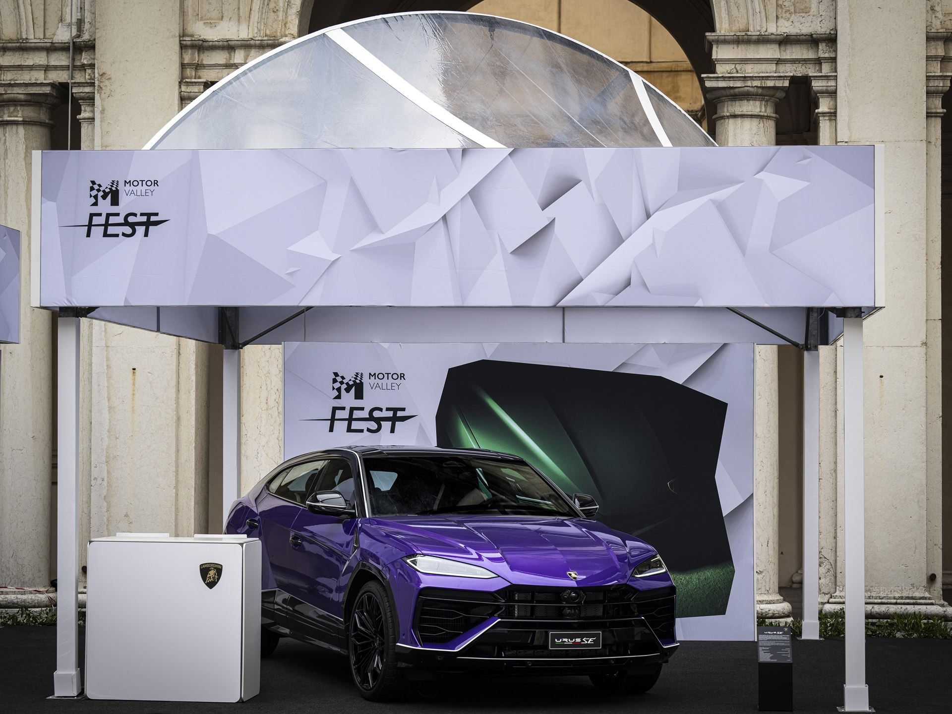 Lamborghini'S Urus Se 'Tettonero' Capsule Turns Motor Valley Fest Into A Masterclass In Bespoke Hybrid Luxury 3 Purple lamborghini urus se tettonero capsule displayed under a white tent at motor valley fest with green lamborghini graphic backdrop