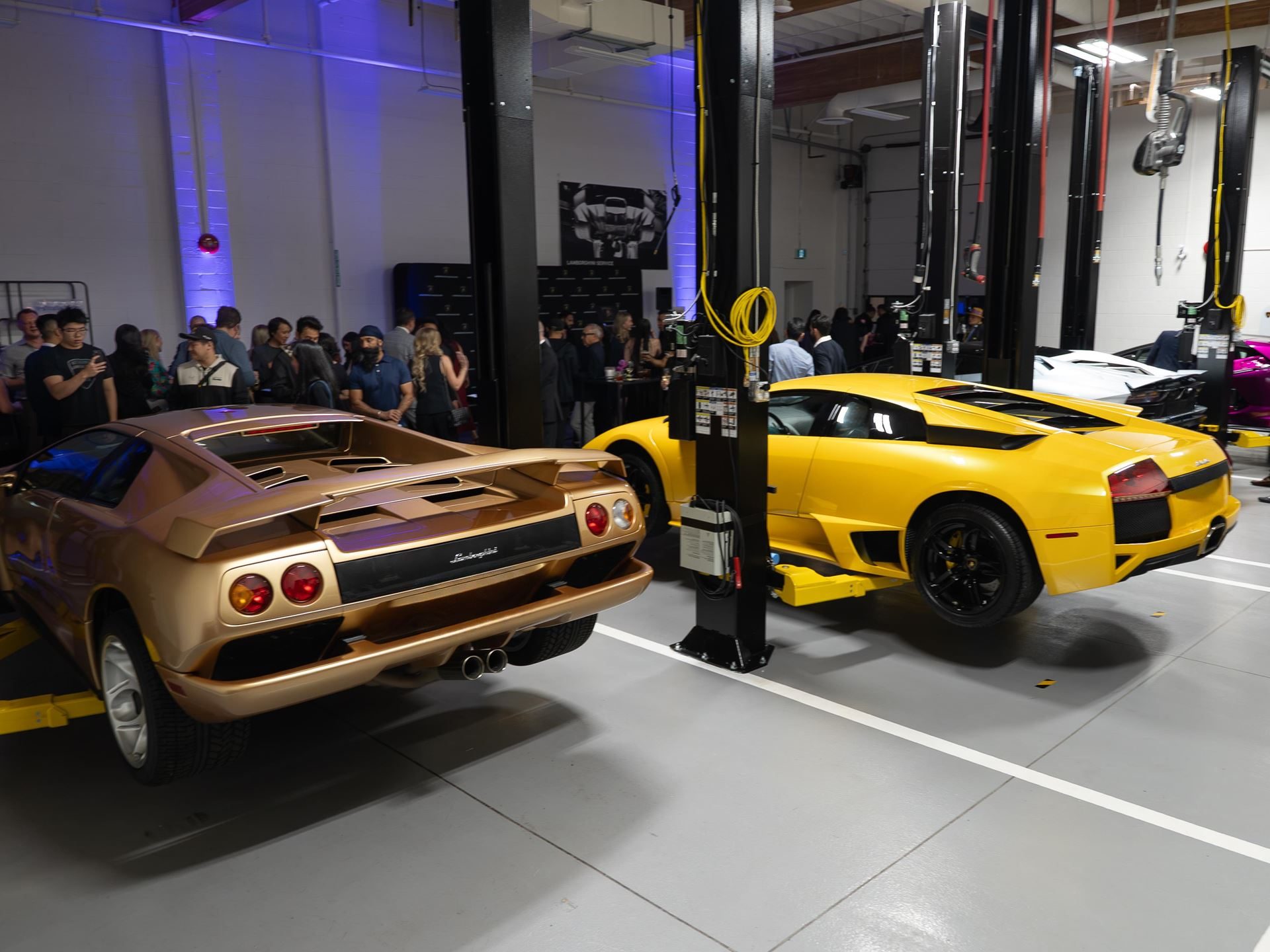 Lamborghini Vancouver'S Expanded Showroom Puts The Full Hybrid Lineup And Six Service Bays Under One Roof 7 A gold lamborghini diablo and yellow murciélago displayed on service lifts during the vancouver showroom opening event