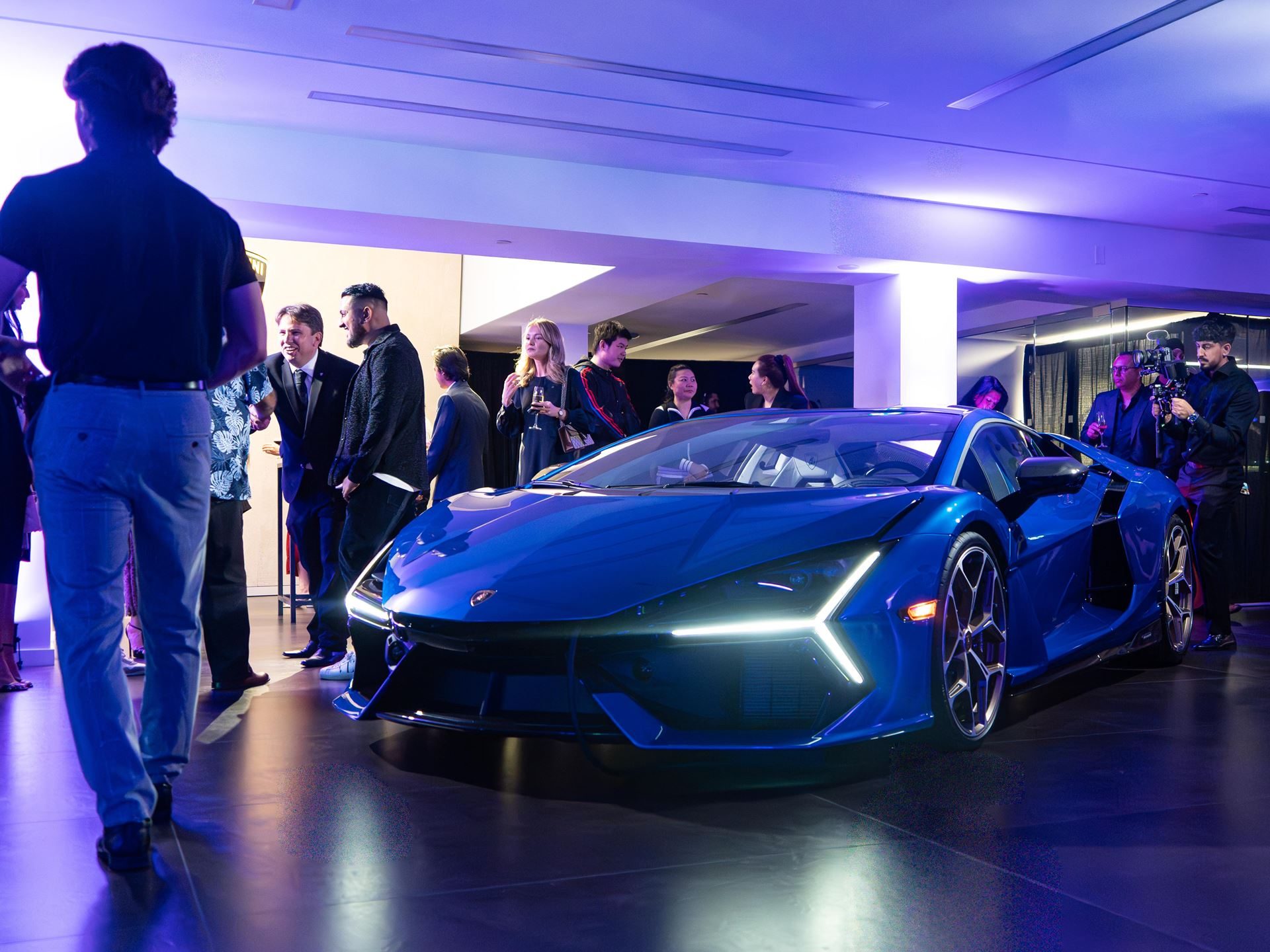 Lamborghini Vancouver'S Expanded Showroom Puts The Full Hybrid Lineup And Six Service Bays Under One Roof 9 Blue lamborghini revuelto on display at the vancouver showroom opening event surrounded by guests in blue lighting