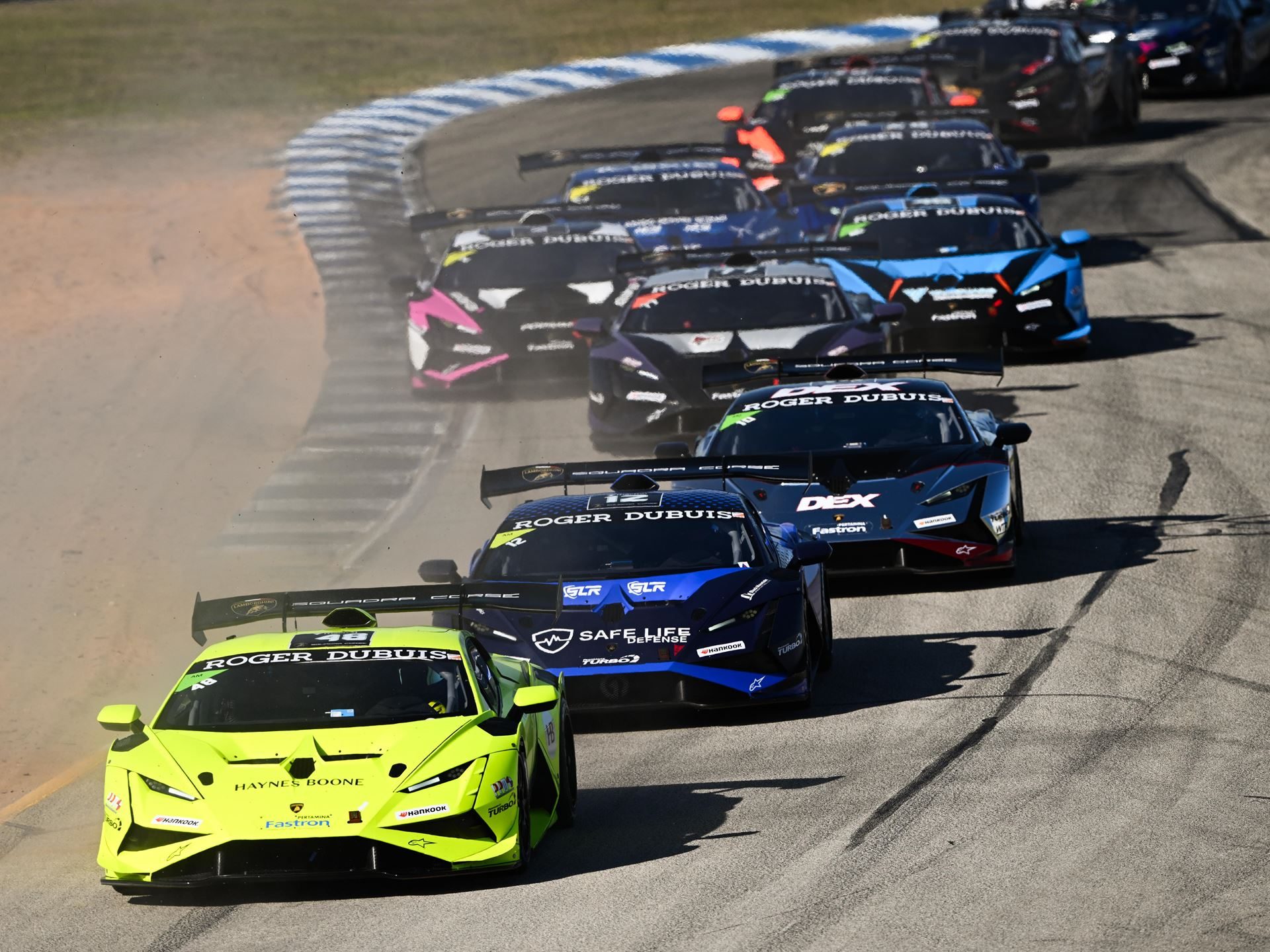 Eight Titles Still On The Line As 132 Drivers Converge On Misano For The 12Th Lamborghini World Finals 7 A lime green lamborghini huracán super trofeo evo2 kicks up dust while leading a line of race cars around a bend