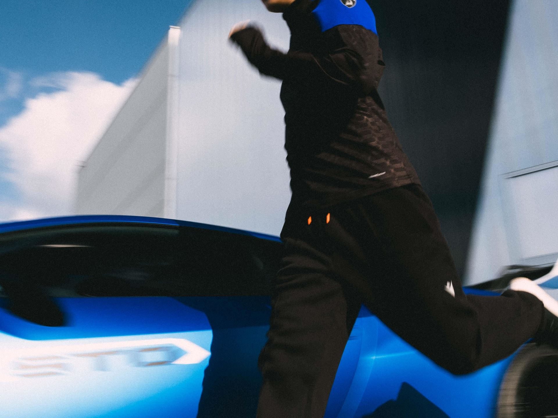 Lamborghini'S Second Macron Activewear Drop Stitches Car-Seat Hexagons Into Running Gear 5 Person in black and blue lamborghini macron activewear running past a blue huracan sto with motion blur