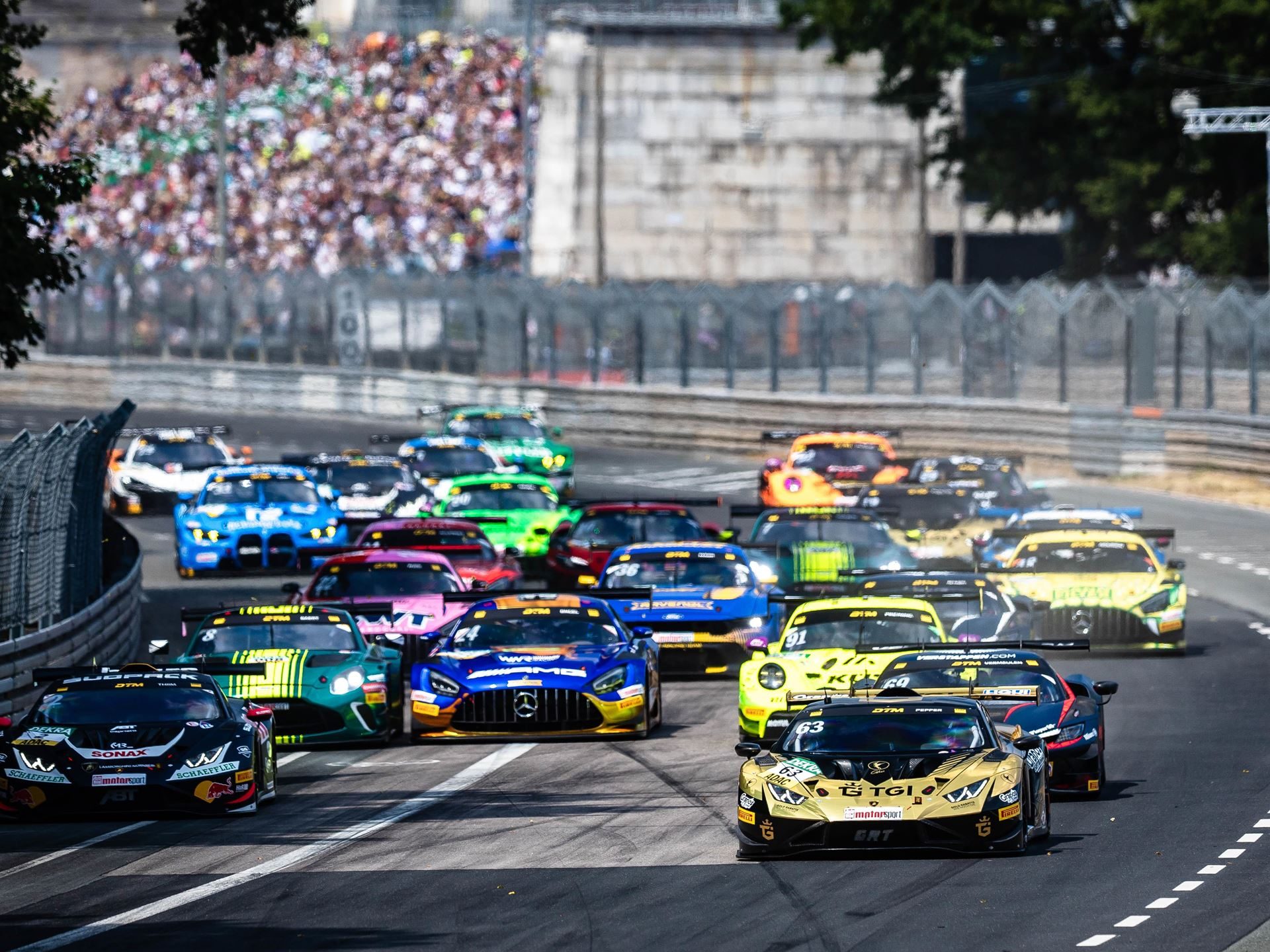 Jordan Pepper'S Norisring Pole-To-Flag Win Puts Lamborghini Back In The Dtm Title Fight 7 A pack of dtm race cars including the gold and black lamborghini huracán gt3 evo2 racing through a bend with spectators in the background