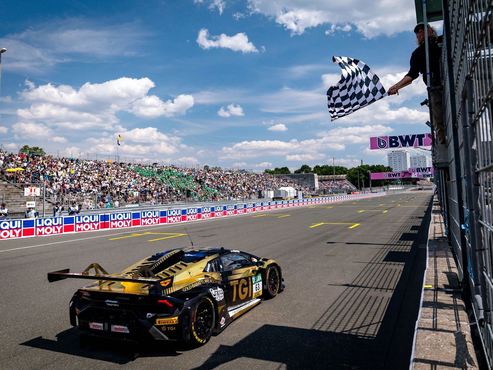 The #63 Lamborghini Huracán GT3 EVO2 crosses the finish line under the checkered flag at the Norisring DTM race