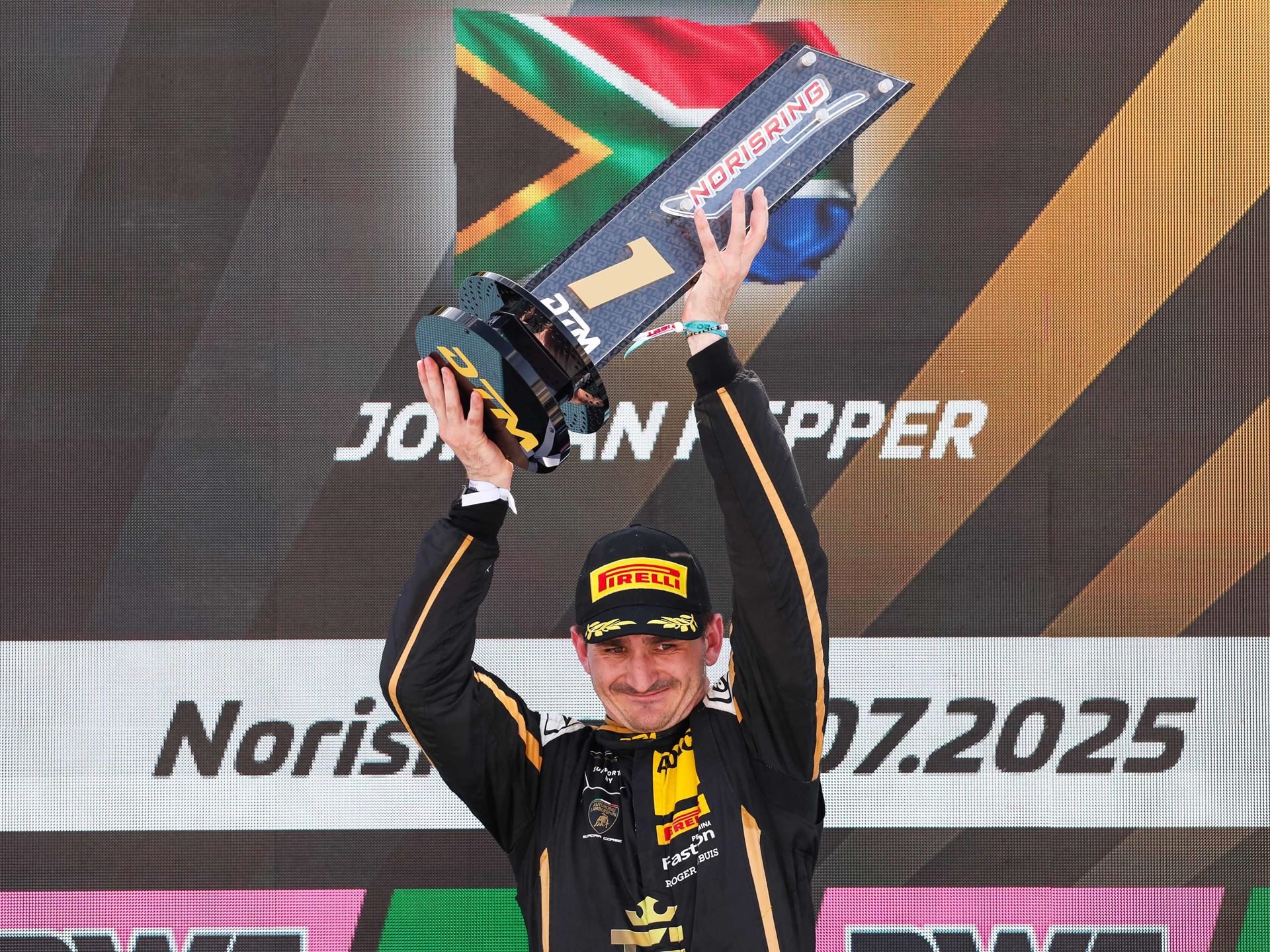 Jordan Pepper'S Norisring Pole-To-Flag Win Puts Lamborghini Back In The Dtm Title Fight 5 Jordan pepper celebrating on the dtm podium, holding a trophy above his head in his black and gold racing suit