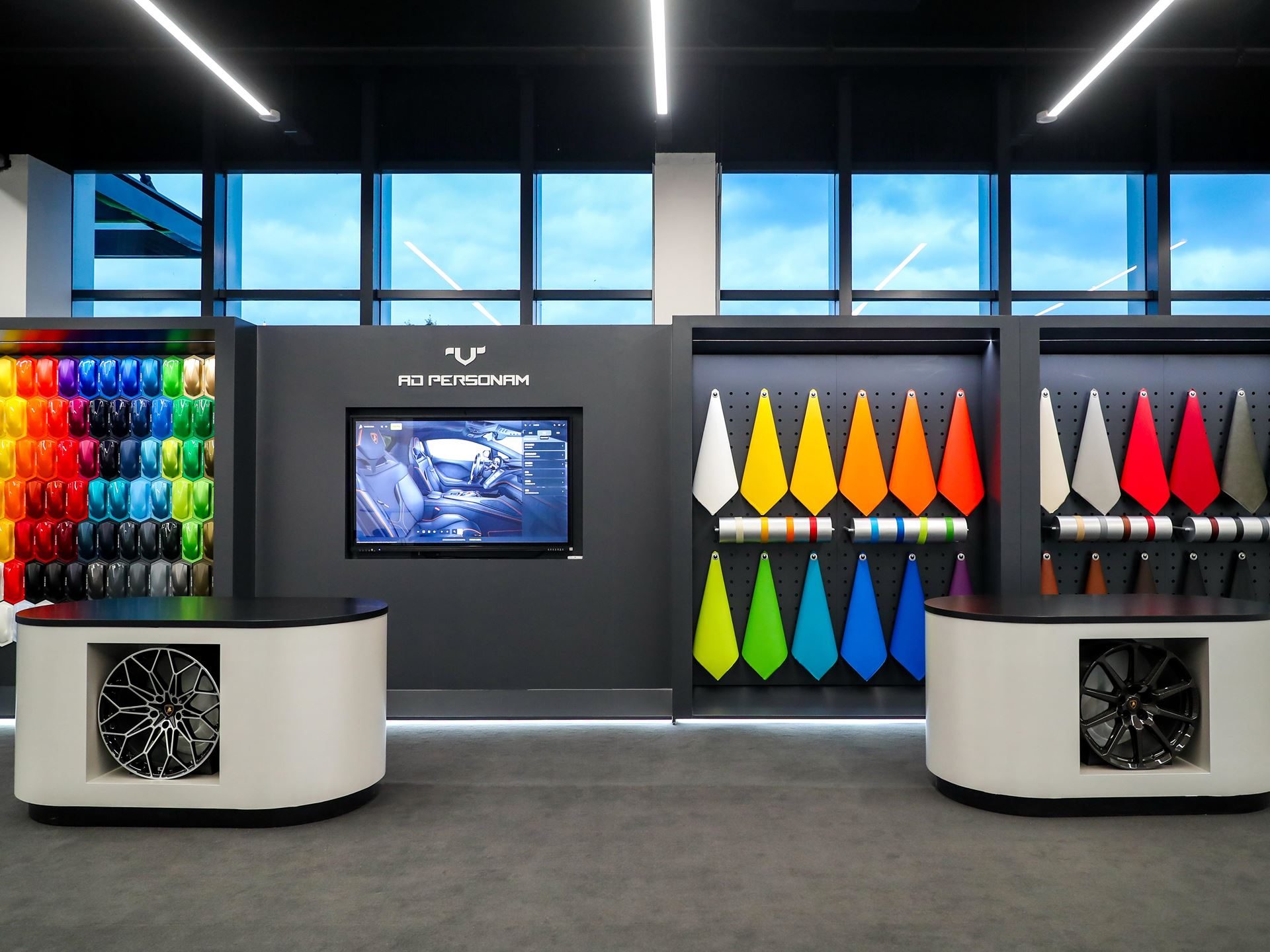 Ad personam customization area showing paint samples, interior material swatches, display wheels, and digital configurator screen
