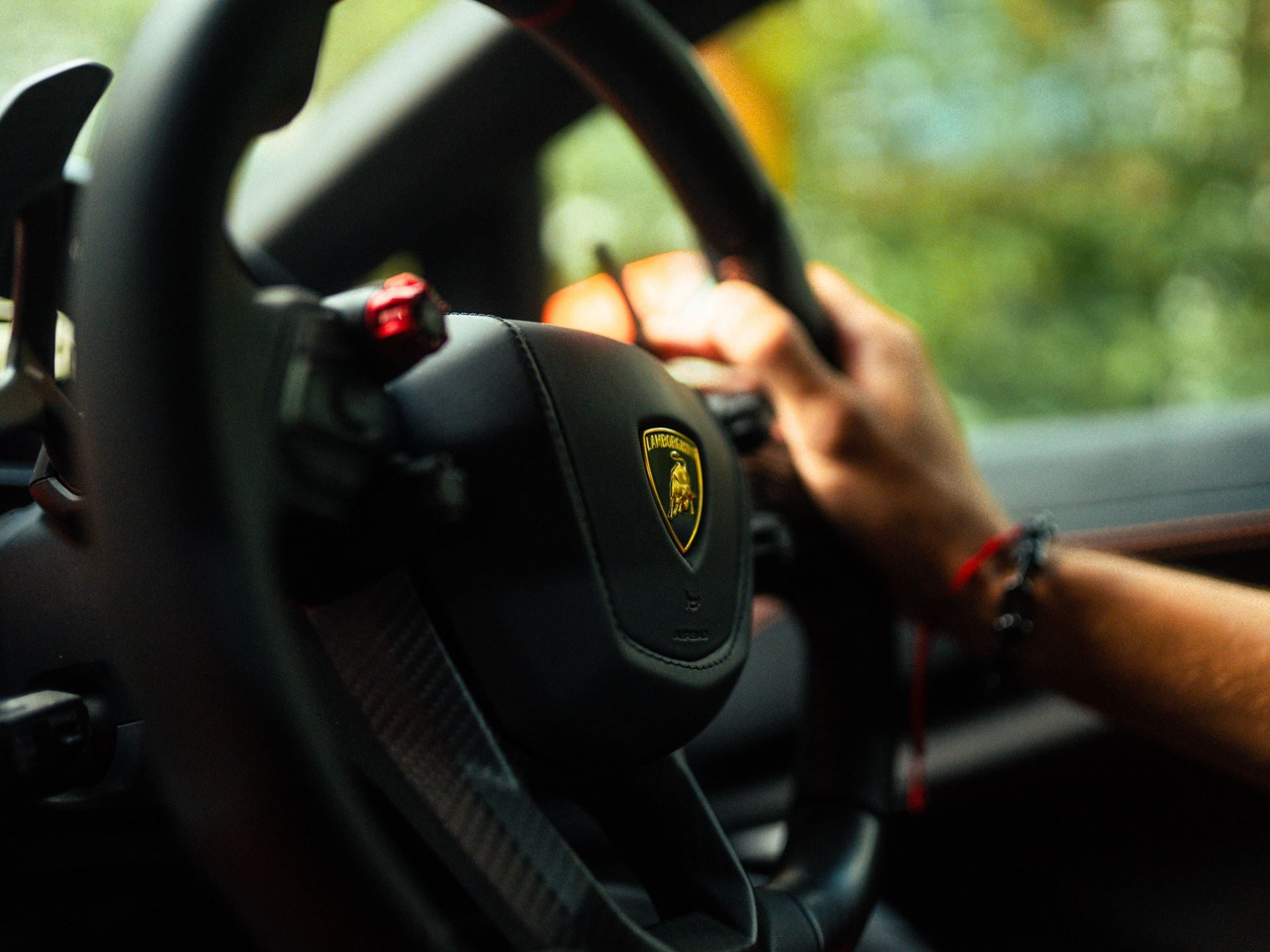 Lamborghini Taps Manchester City'S Rúben Dias To Front Its 1,001-Hp Flagship 9 Close-up of a hand on a lamborghini steering wheel showing the brand emblem, carbon fiber trim, and red accent buttons