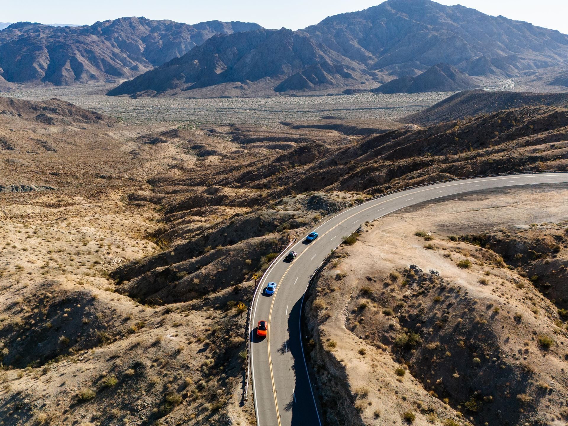 Shedrives A Lambo Is Not Just A Feel-Good Event. It Is Lamborghini'S Play For Long-Term Loyalty. 5 Aerial view of a convoy of lamborghini revueltos and a urus driving along a winding road through an arid mountain landscape