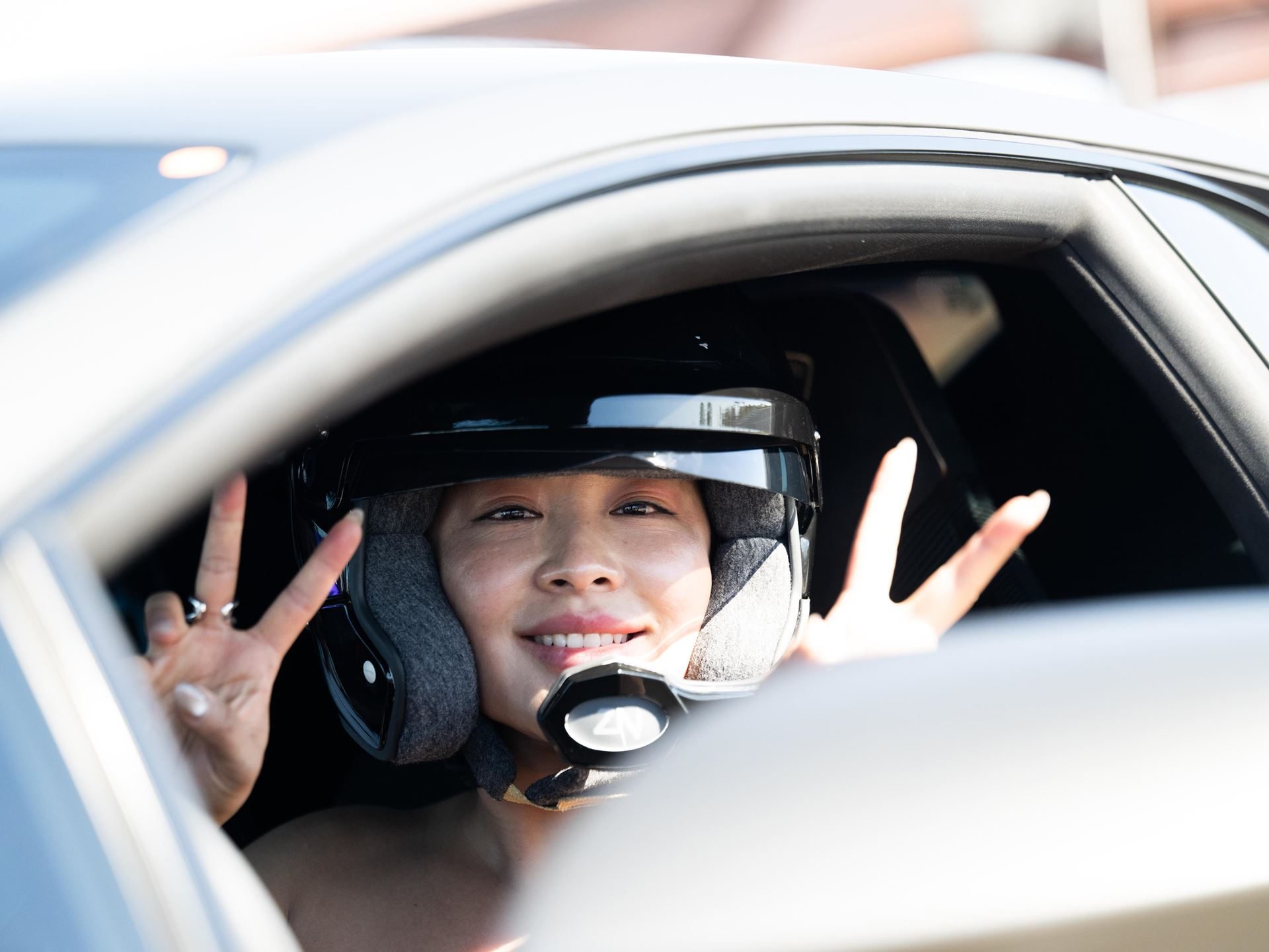 Shedrives A Lambo Is Not Just A Feel-Good Event. It Is Lamborghini'S Play For Long-Term Loyalty. 11 Woman wearing a racing helmet smiling and making peace signs from the window of a car at the shedrives a lambo event
