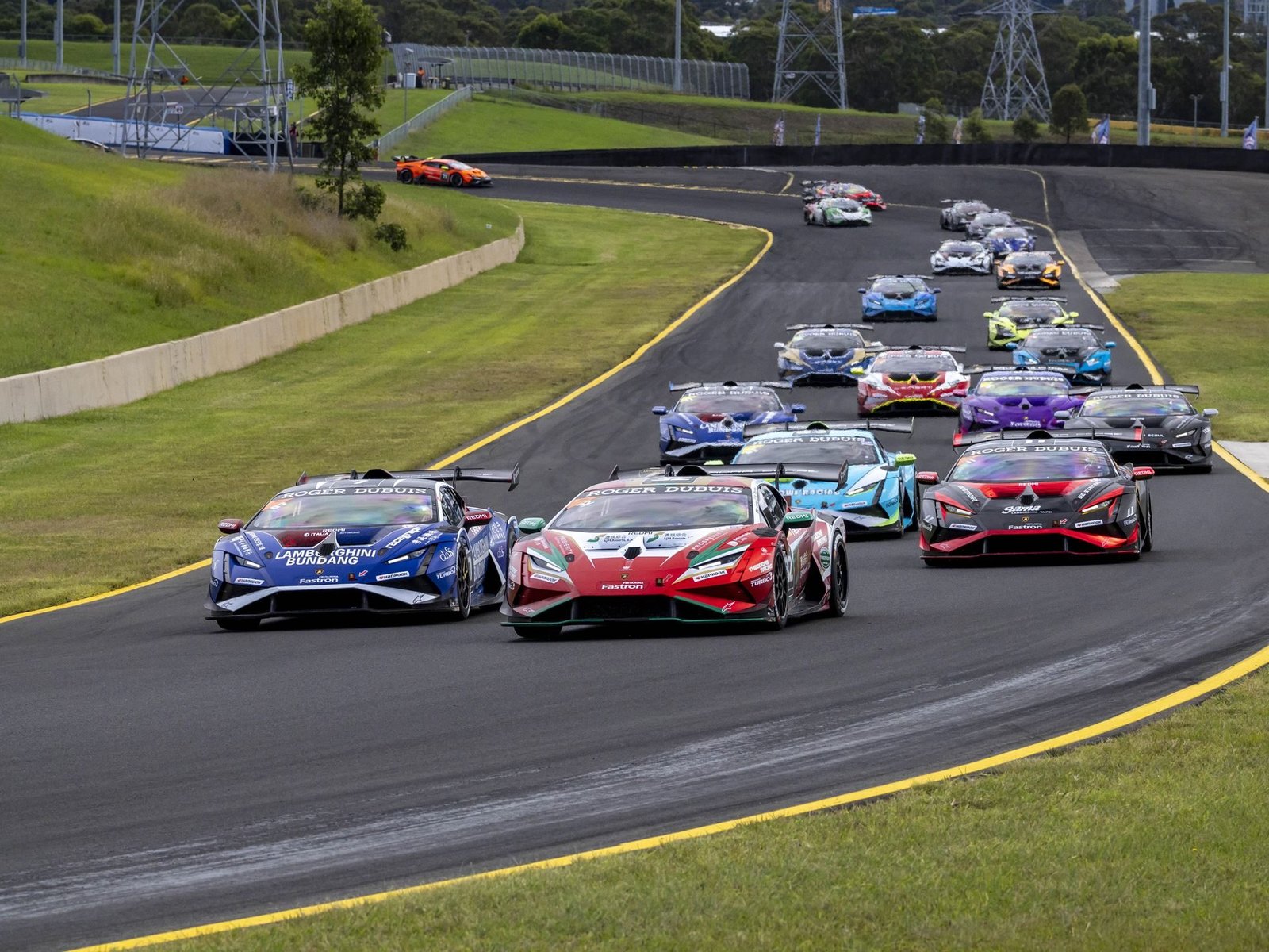 Multiple Lamborghini Huracán Super Trofeo EVO2 race cars navigate a turn during a Super Trofeo Asia round, showing aggressive aero kits and large rear wings