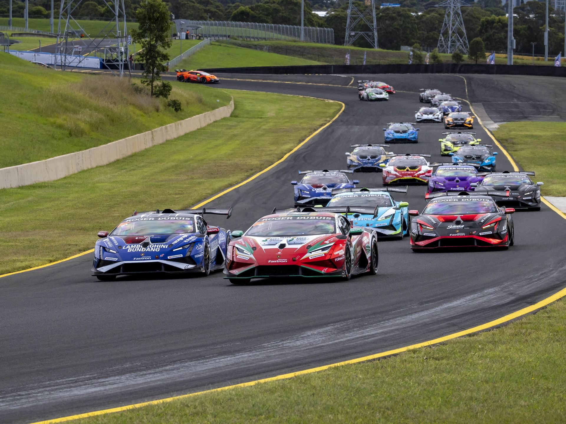 Multiple lamborghini huracán super trofeo evo2 race cars navigate a turn during a super trofeo asia round, showing aggressive aero kits and large rear wings